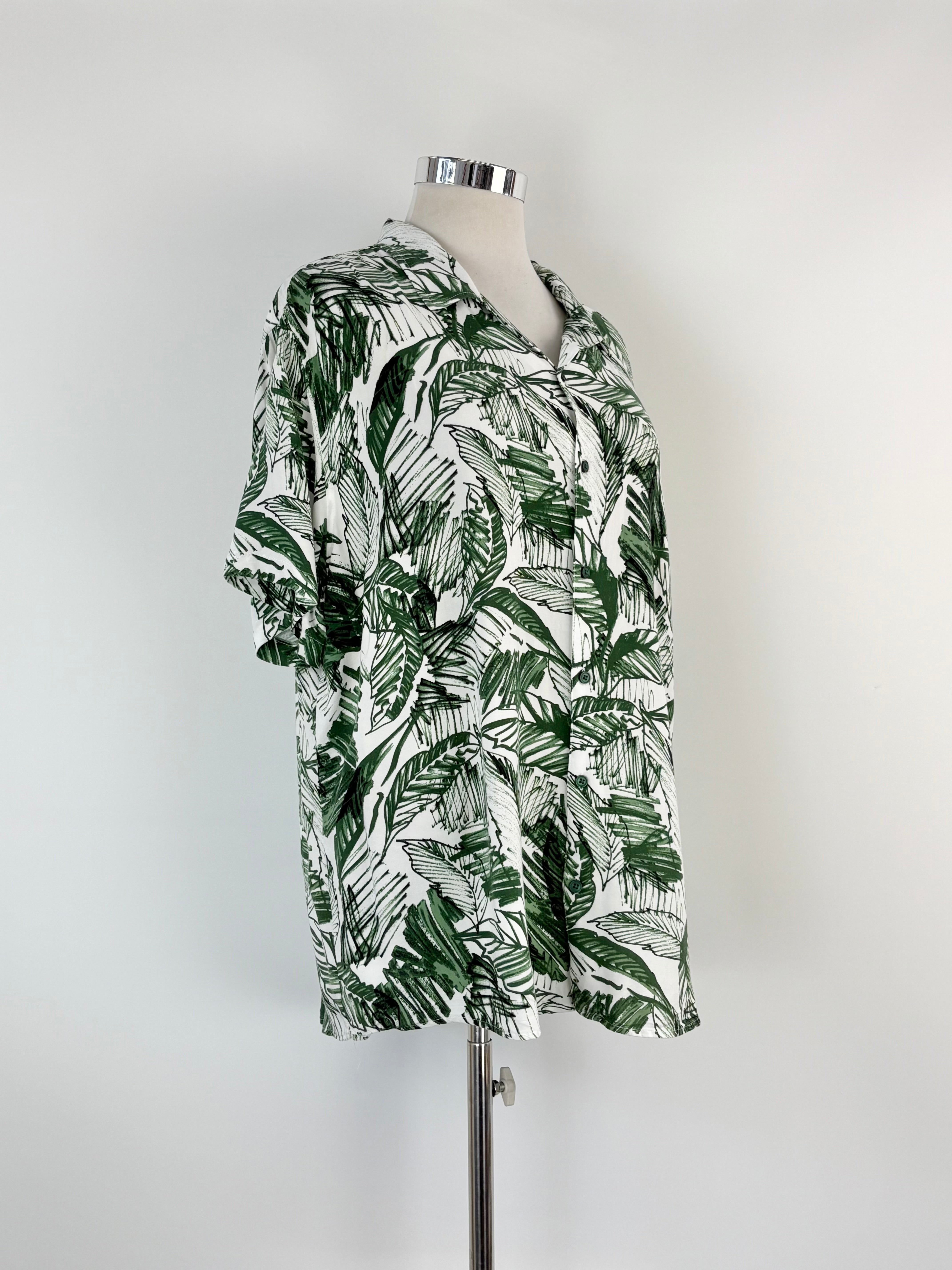Green and white leaf patterned shirt on a mannequin against a gray background