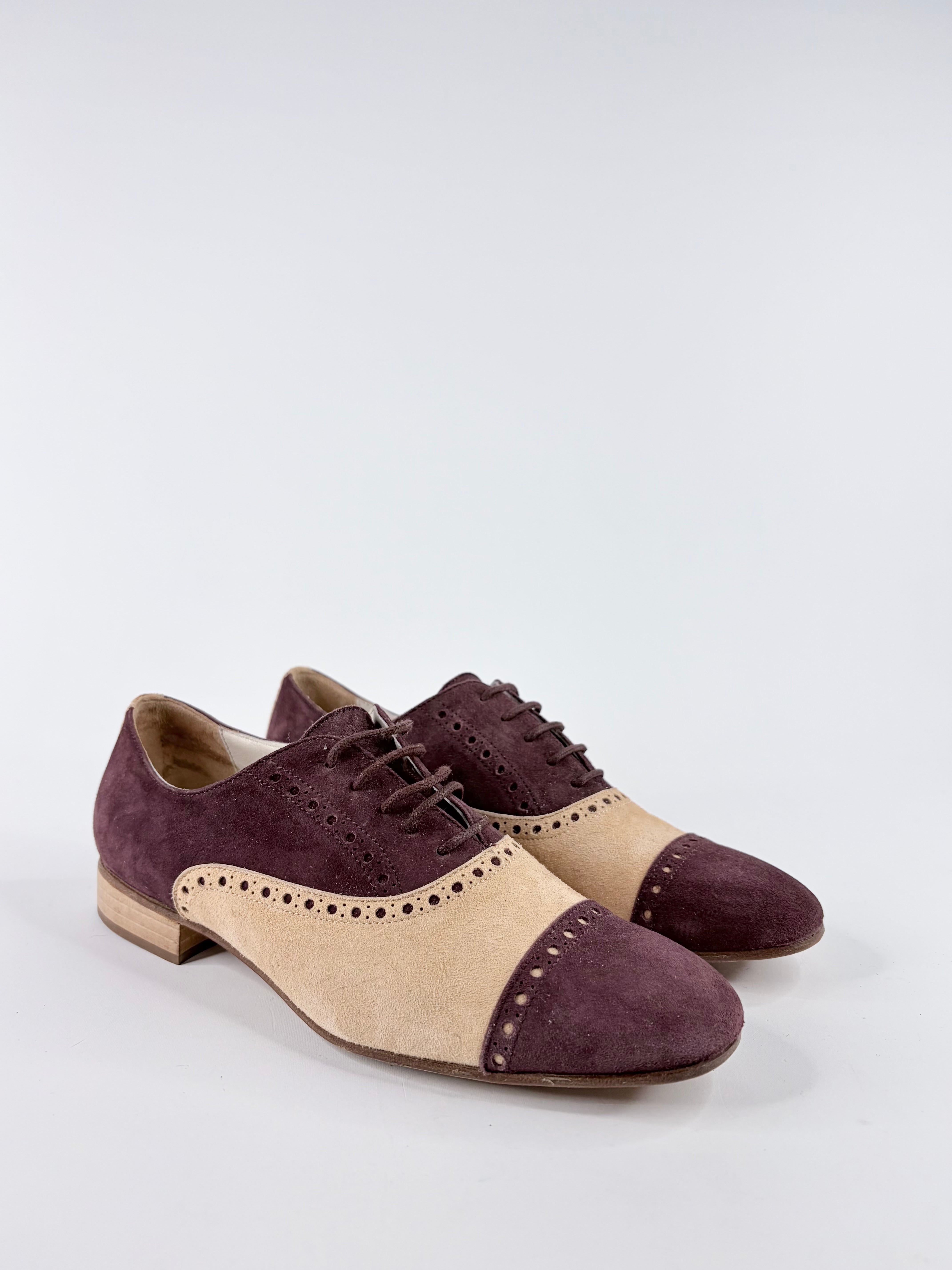 Two shoes with a two-tone design, one beige and one brown, on a light gray background.
