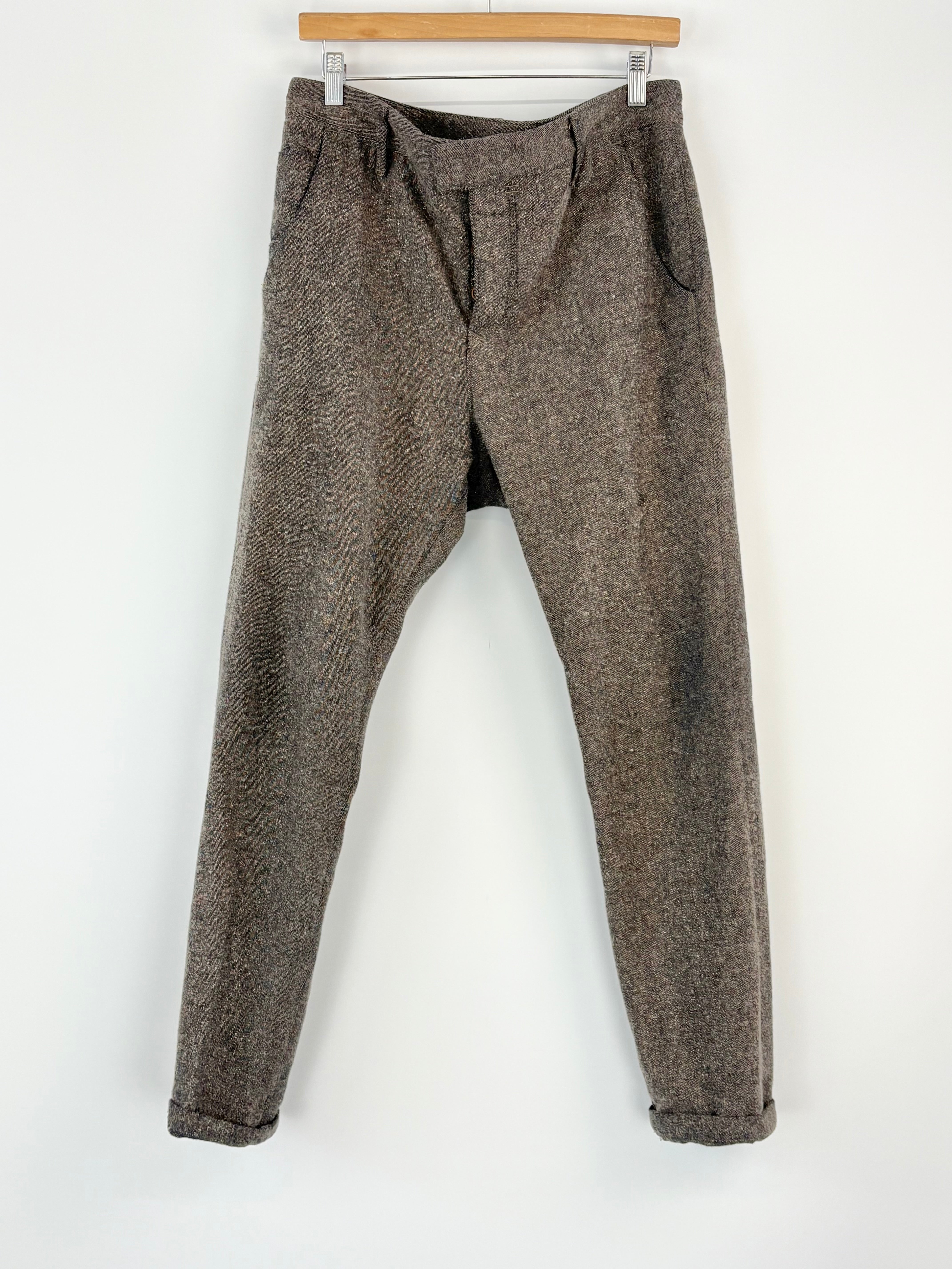 Grey tweed pants hanging on a white background