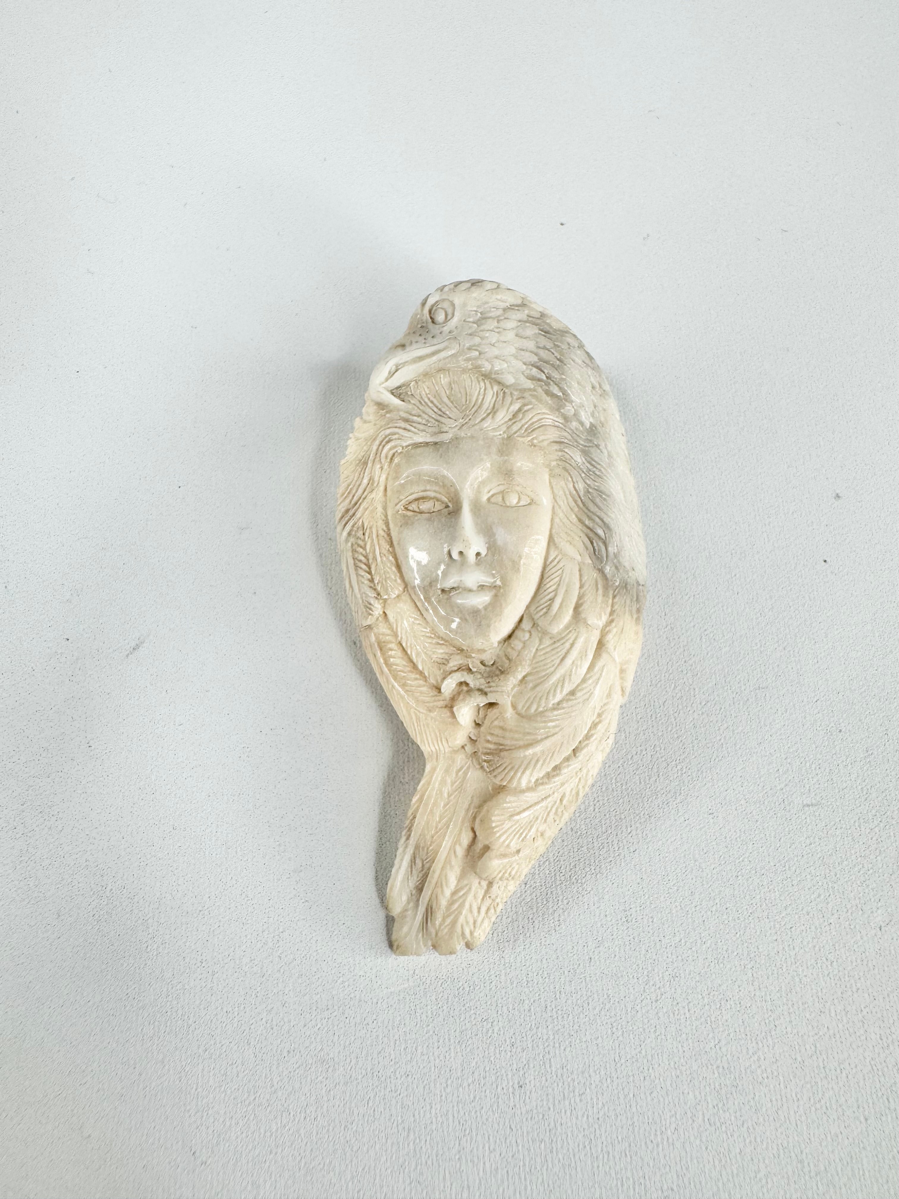 Carved figure of a face on a shell against a light gray background