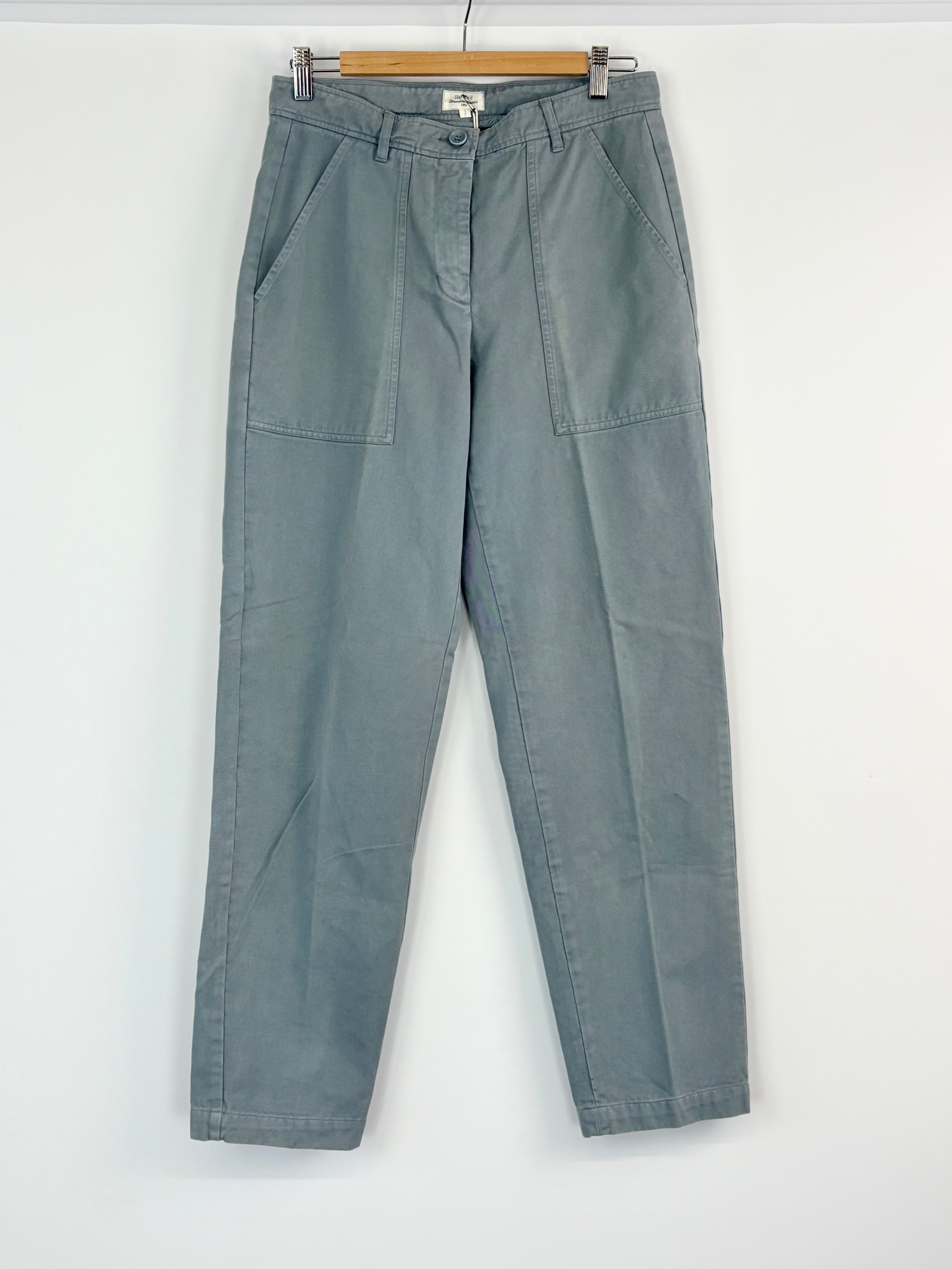 Blue pants hanging on a wooden hanger against a white background