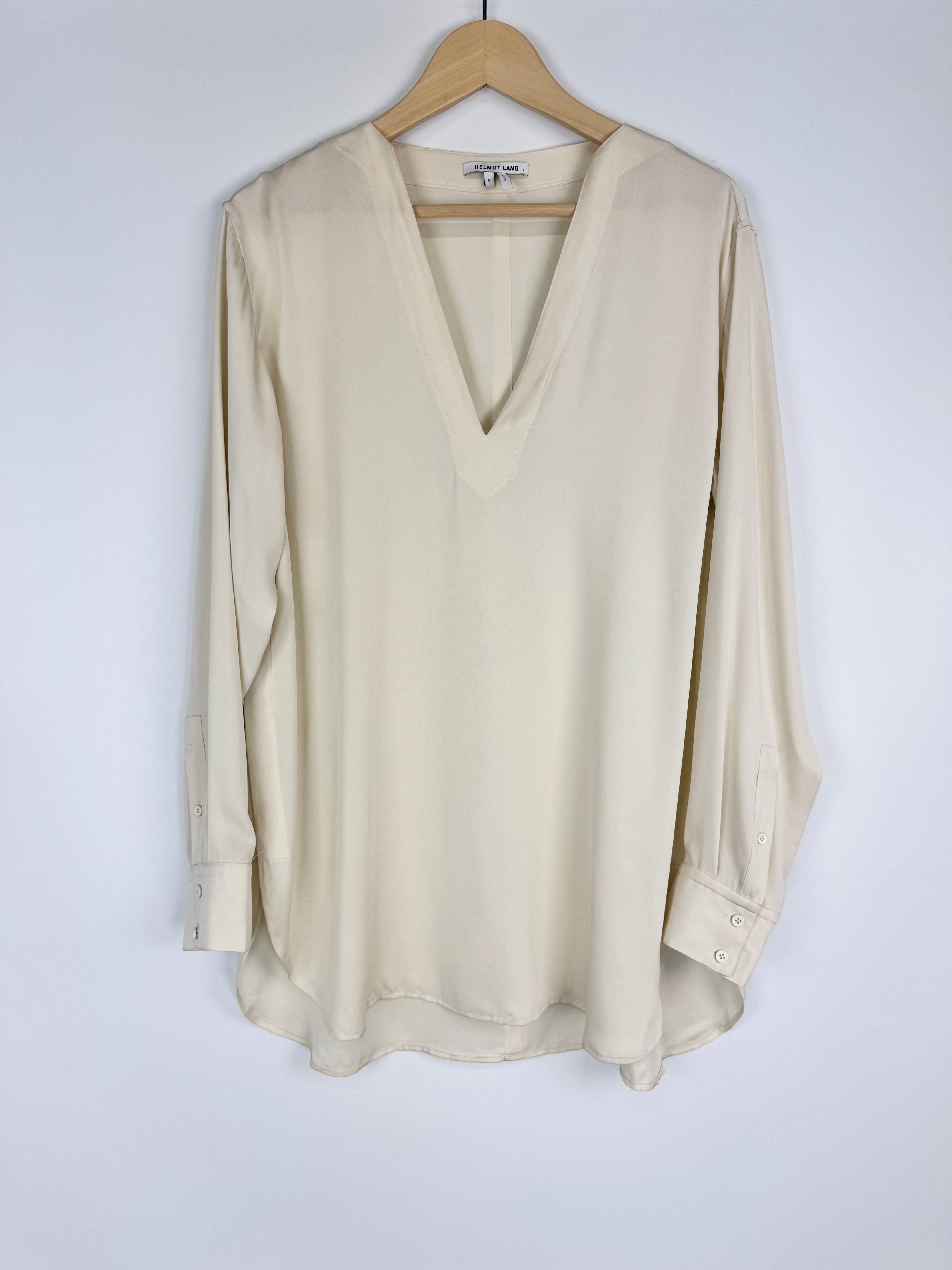 Beige blouse on a wooden hanger against a white background