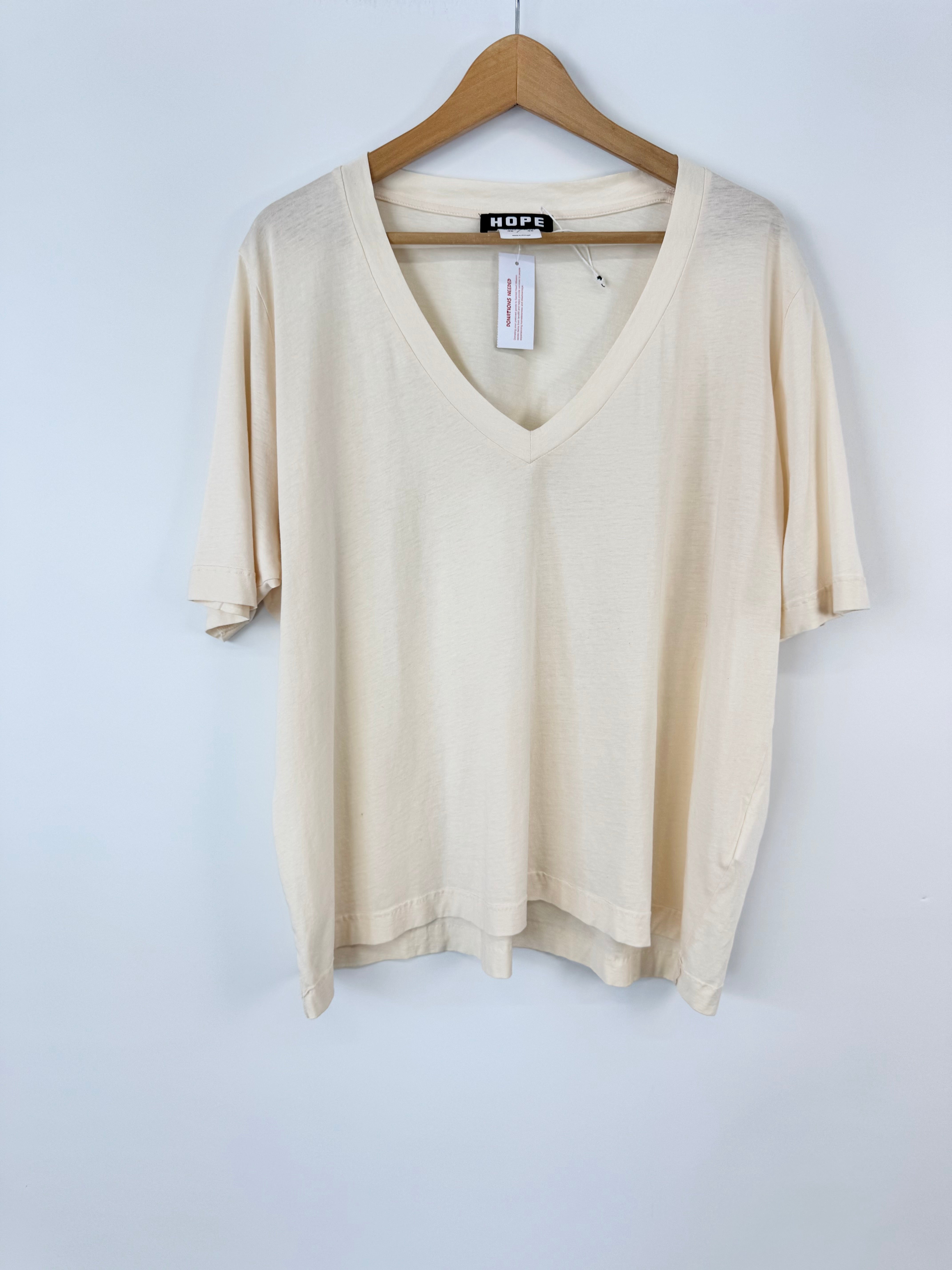 Beige v-neck shirt on a hanger against a light blue background