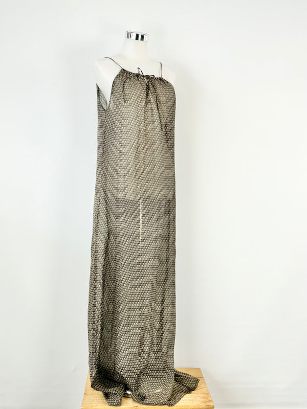 A long maxi beach dress displayed on a mannequin, featuring a halter neck and fine string ties at the front.