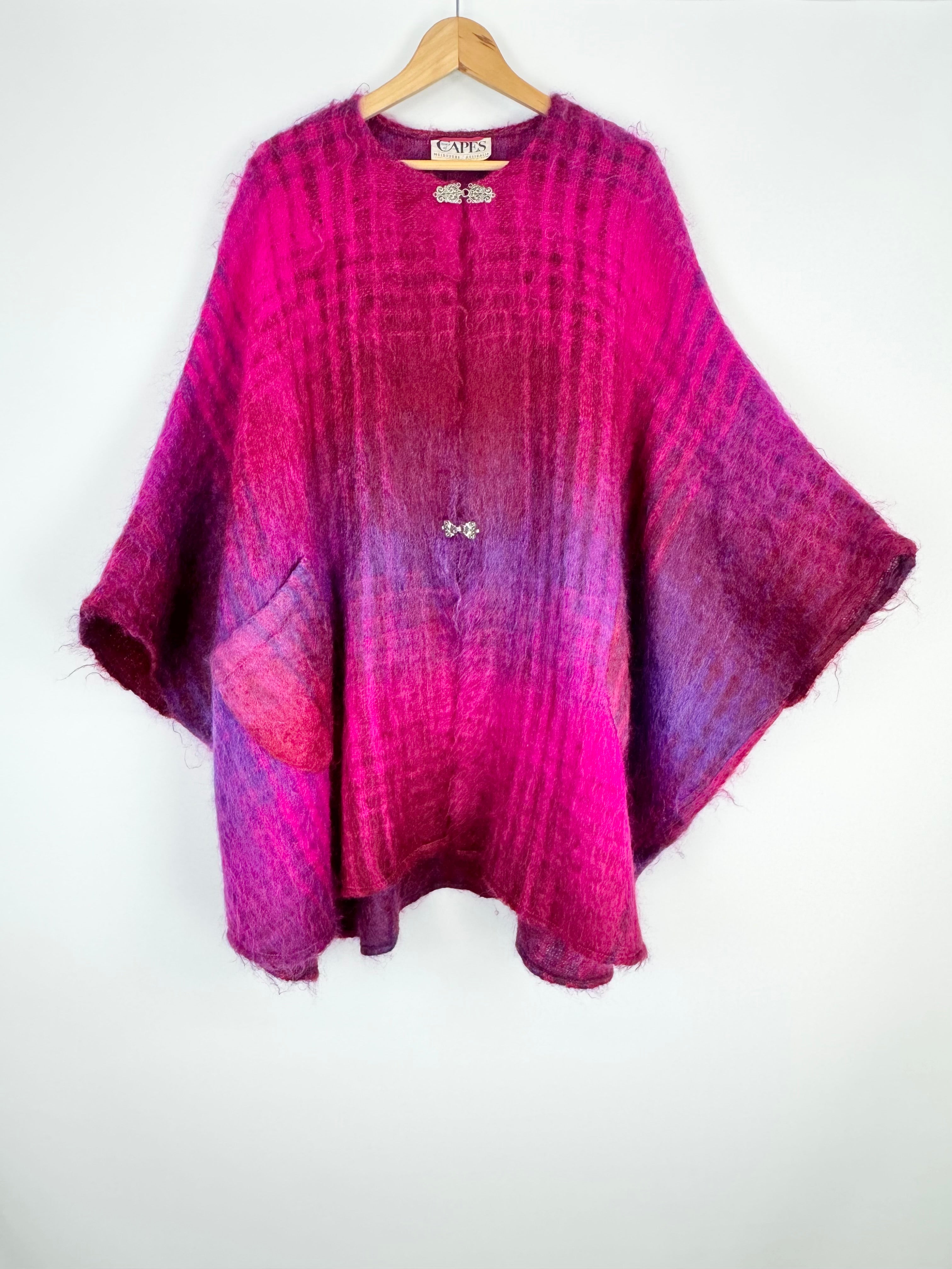 Purple and pink gradient poncho on a hanger against a white background