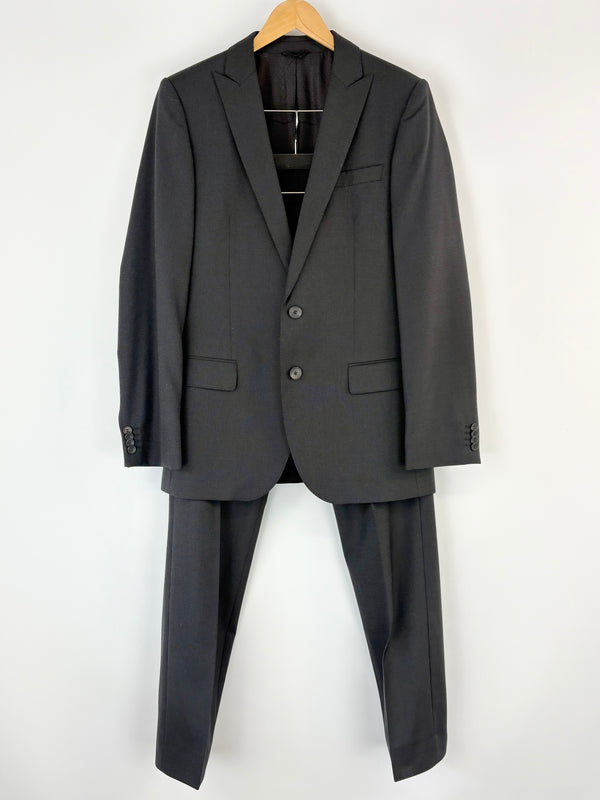 Black Hugo Boss suit jacket and pants on a hanger against a white background