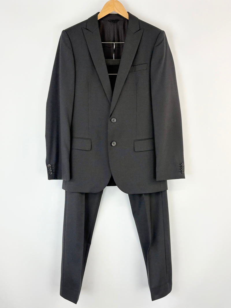 Black Hugo Boss suit jacket and pants on a hanger against a white background