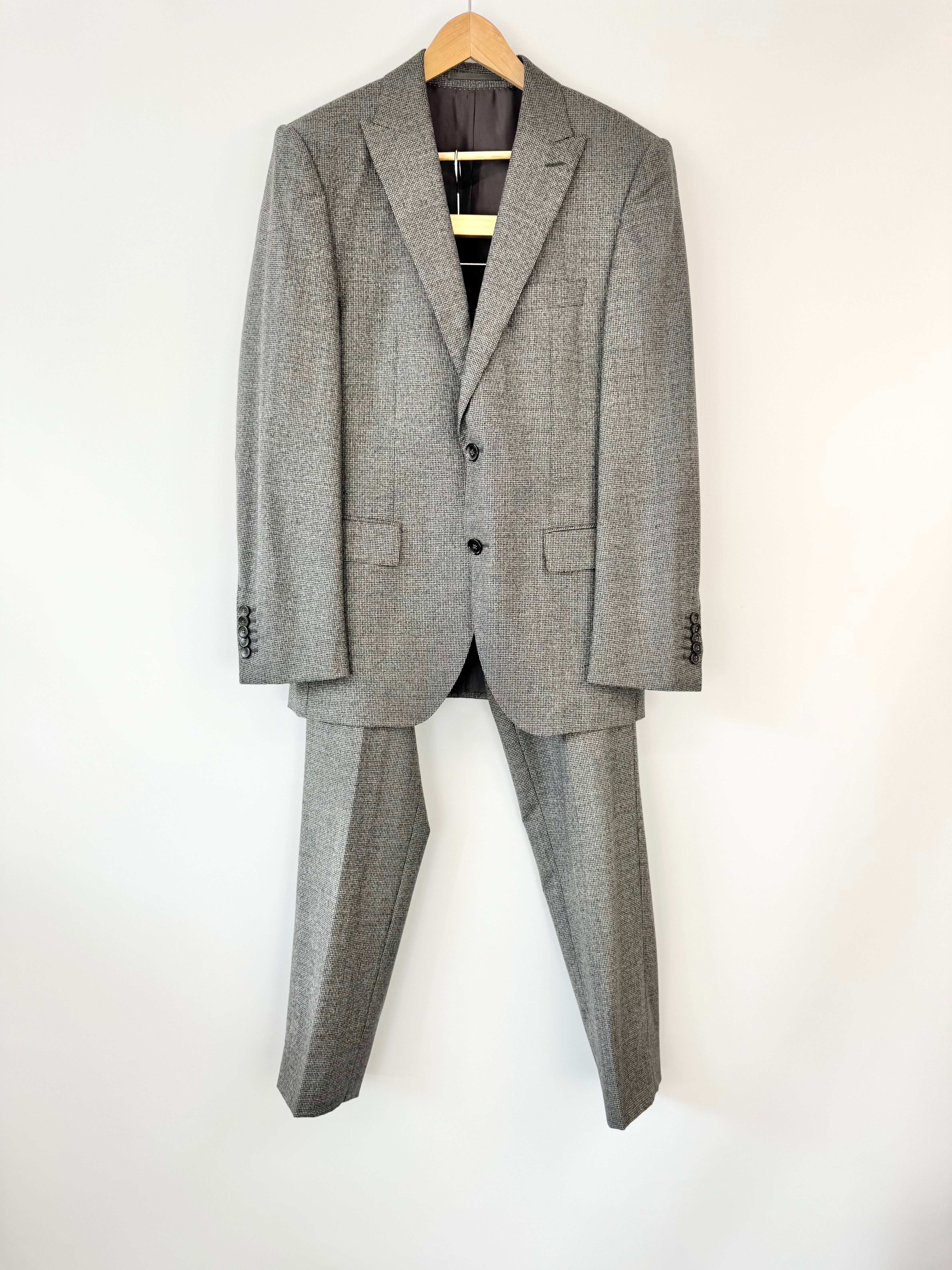 Gray micro houndstooth patterned suit on a hanger against a white background