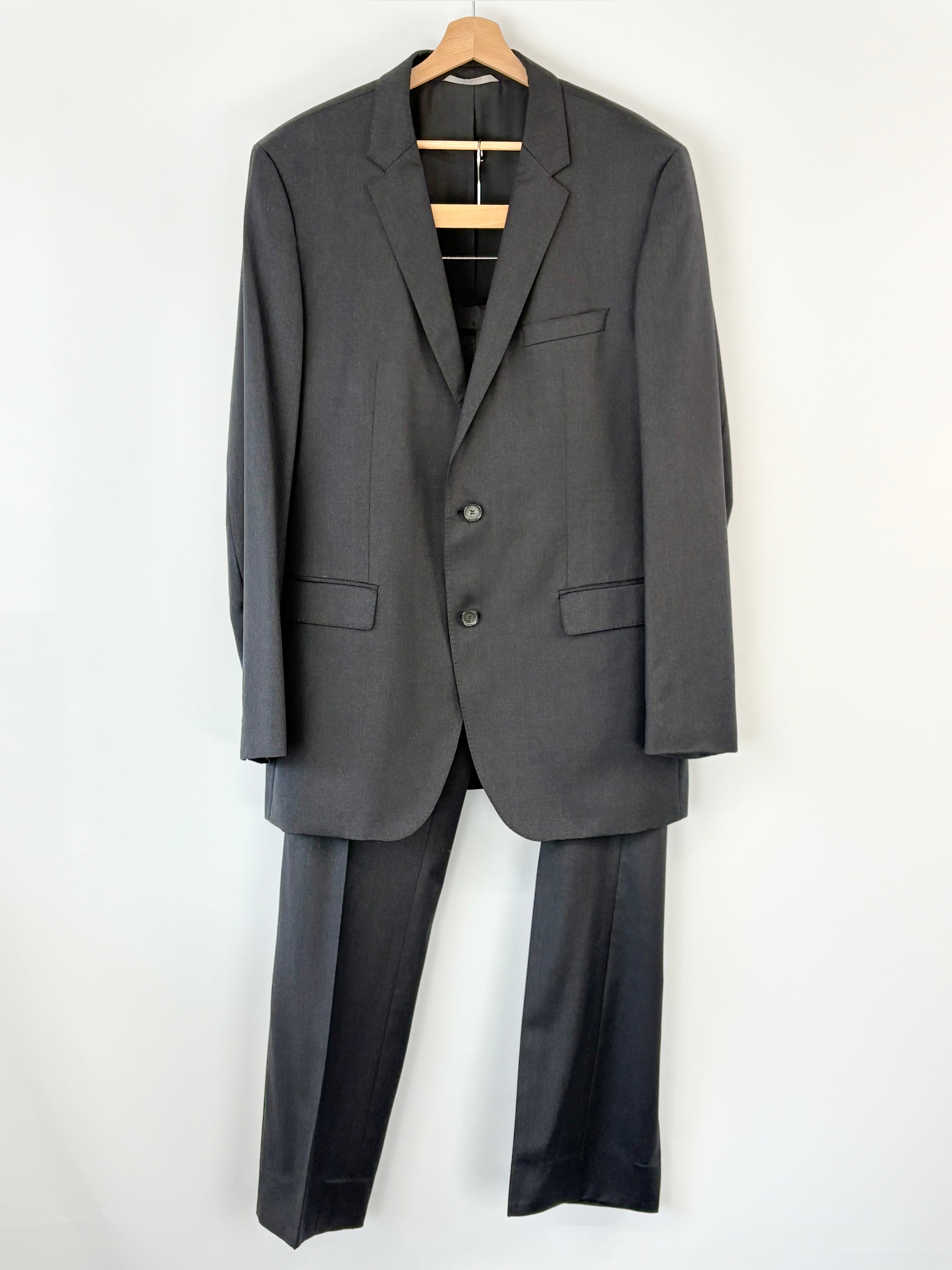 Charcoal suit on a hanger against a white background