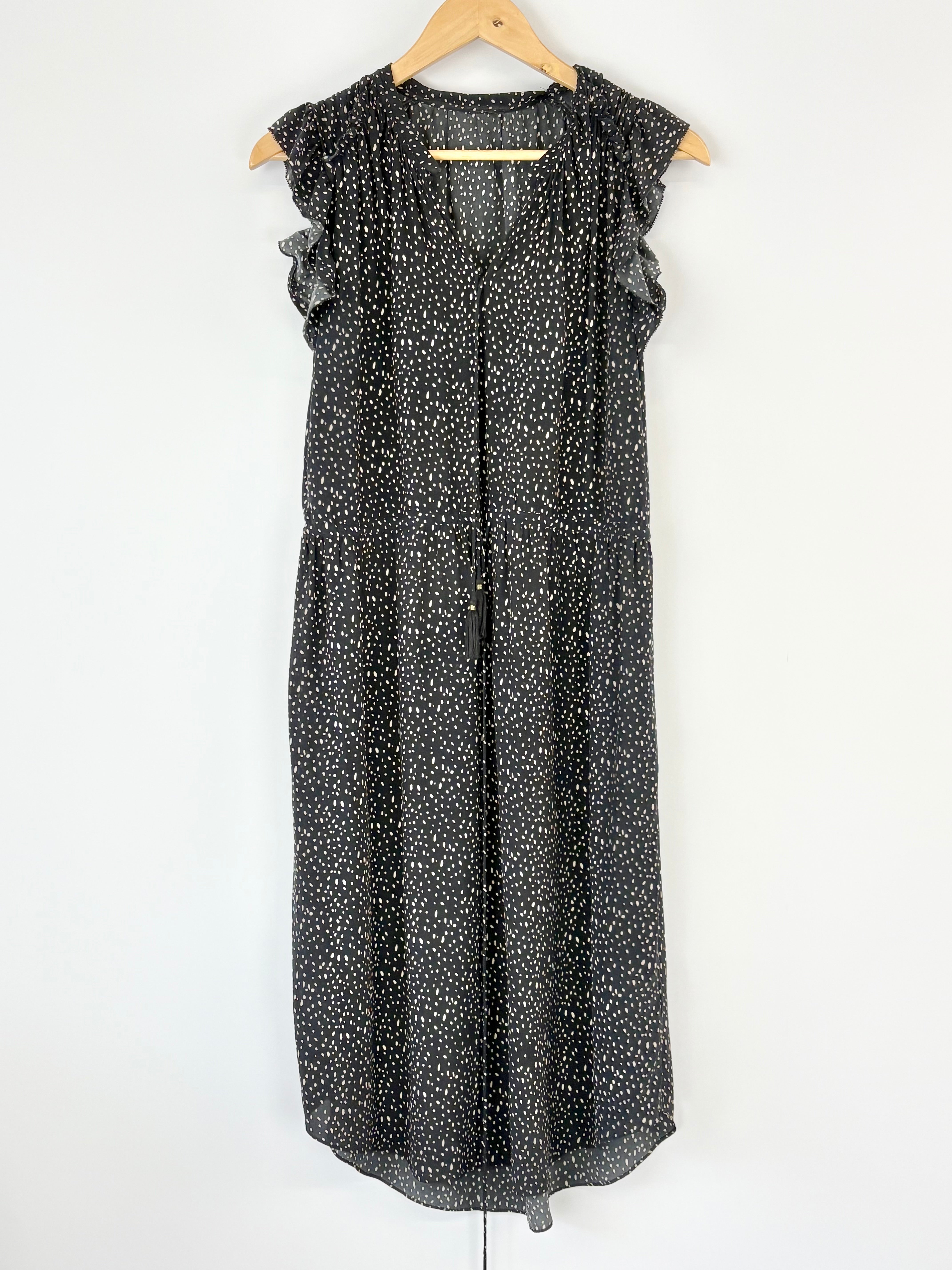 Black and white dotted dress on a hanger against a white background