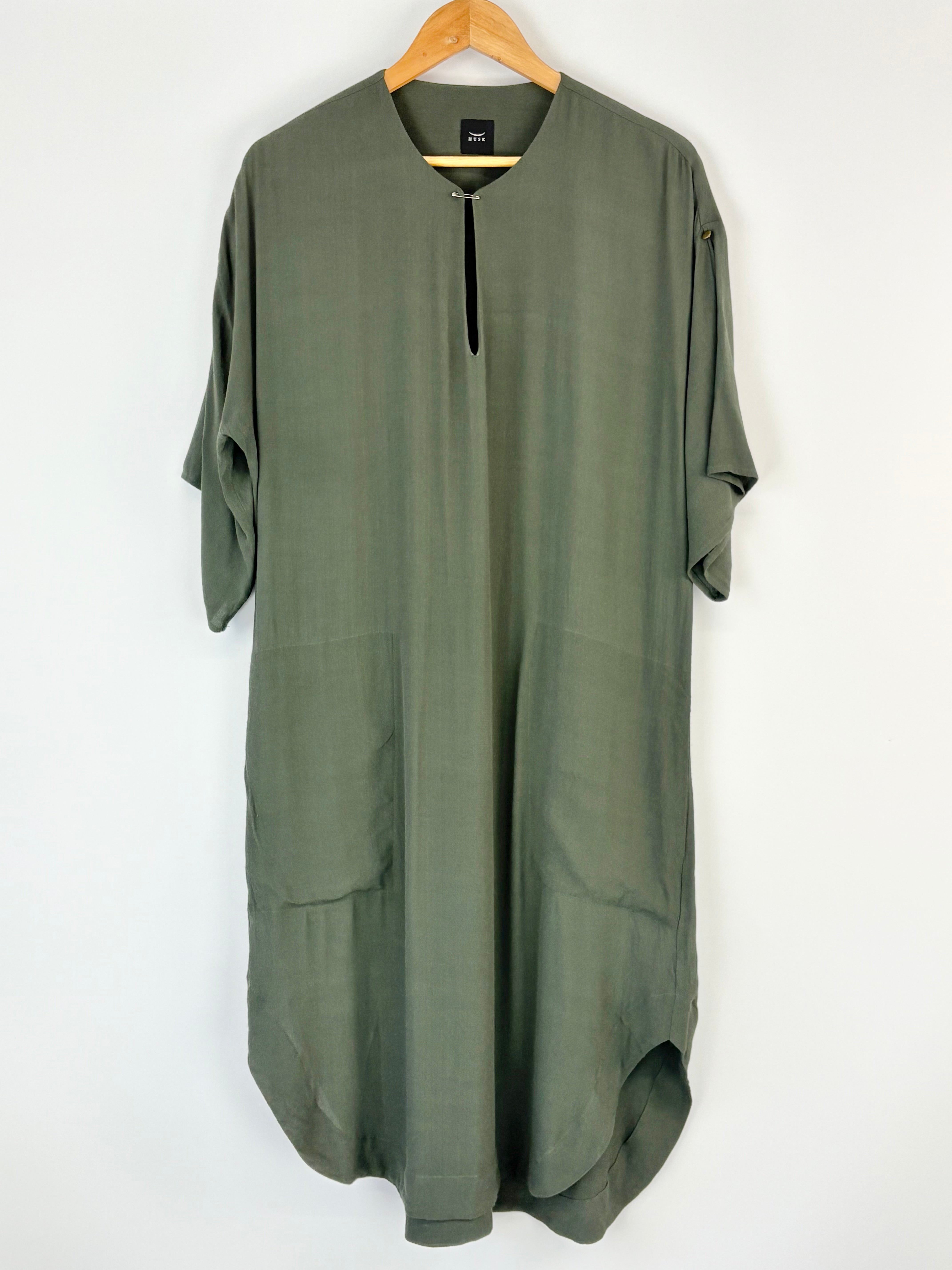 Green Husk dress on a hanger against a white background