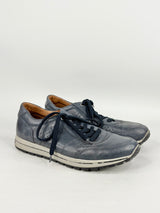 Pair of blue sneakers with dark laces on a light gray background
