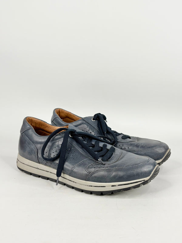 Pair of blue sneakers with dark laces on a light gray background