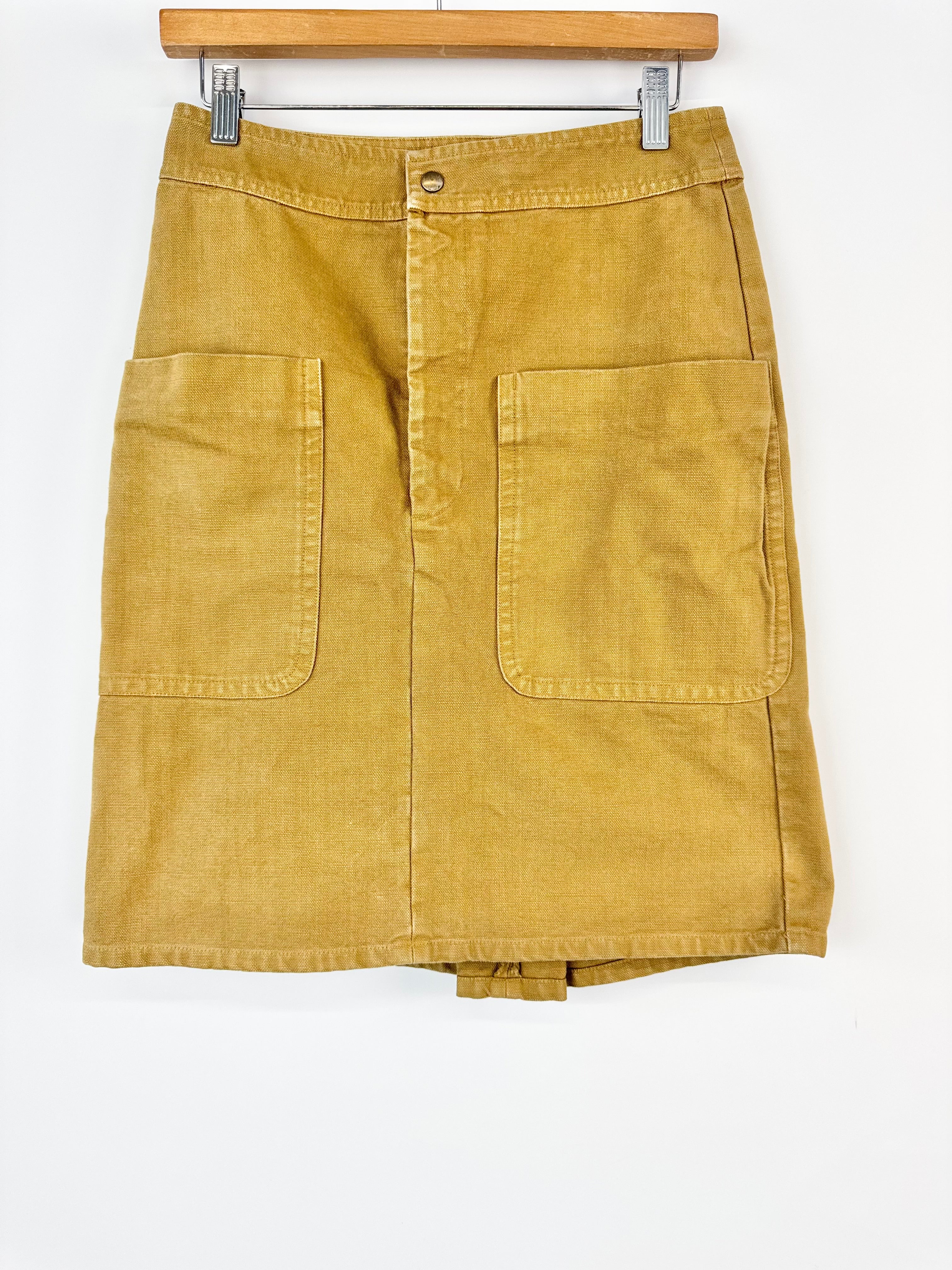 Mustard yellow skirt on a hanger against a white background