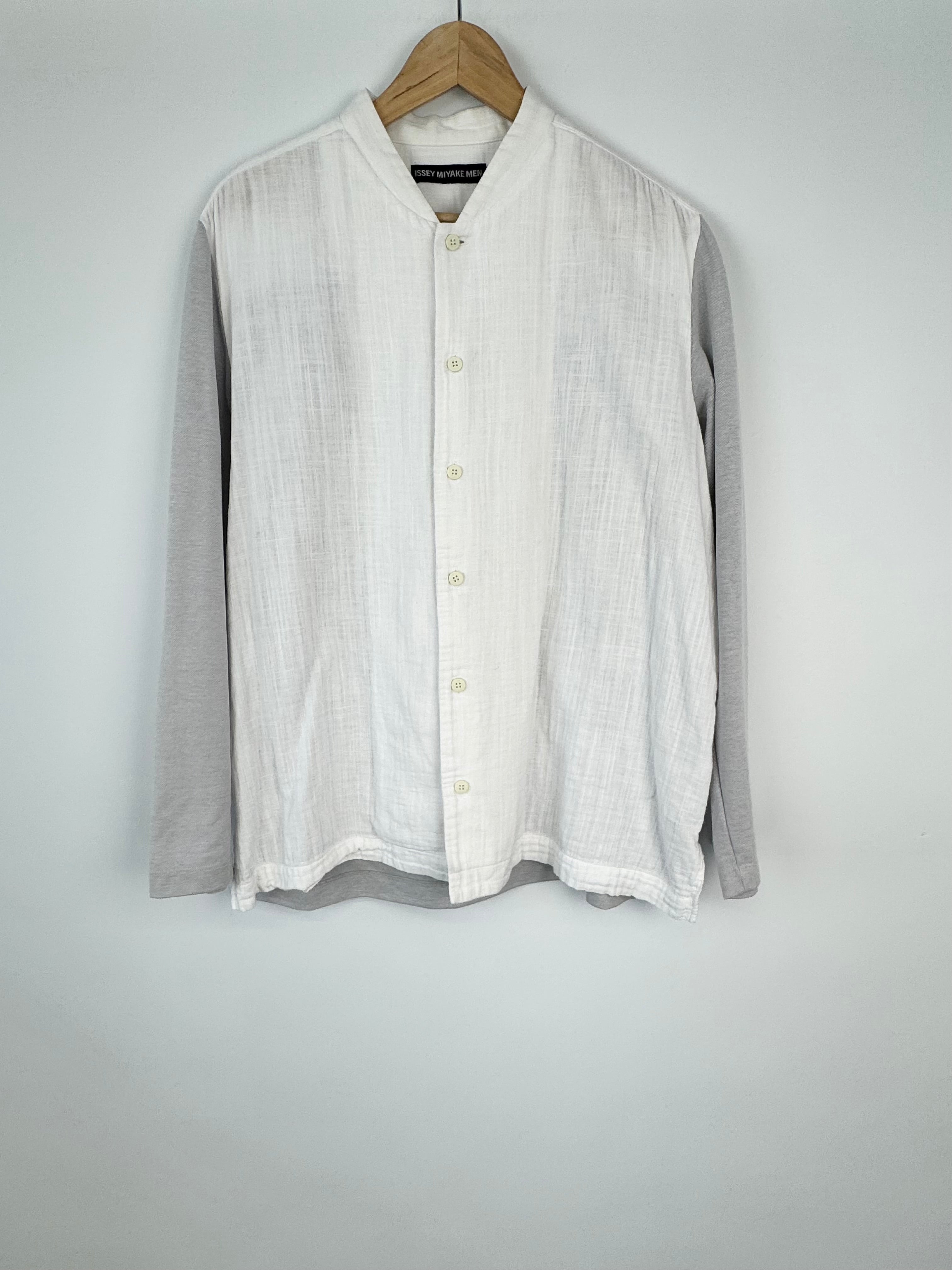 White button-up shirt on a hanger against a gray background