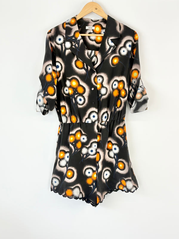 Black playsuit with orange and white abstract pattern on a hanger against a white background