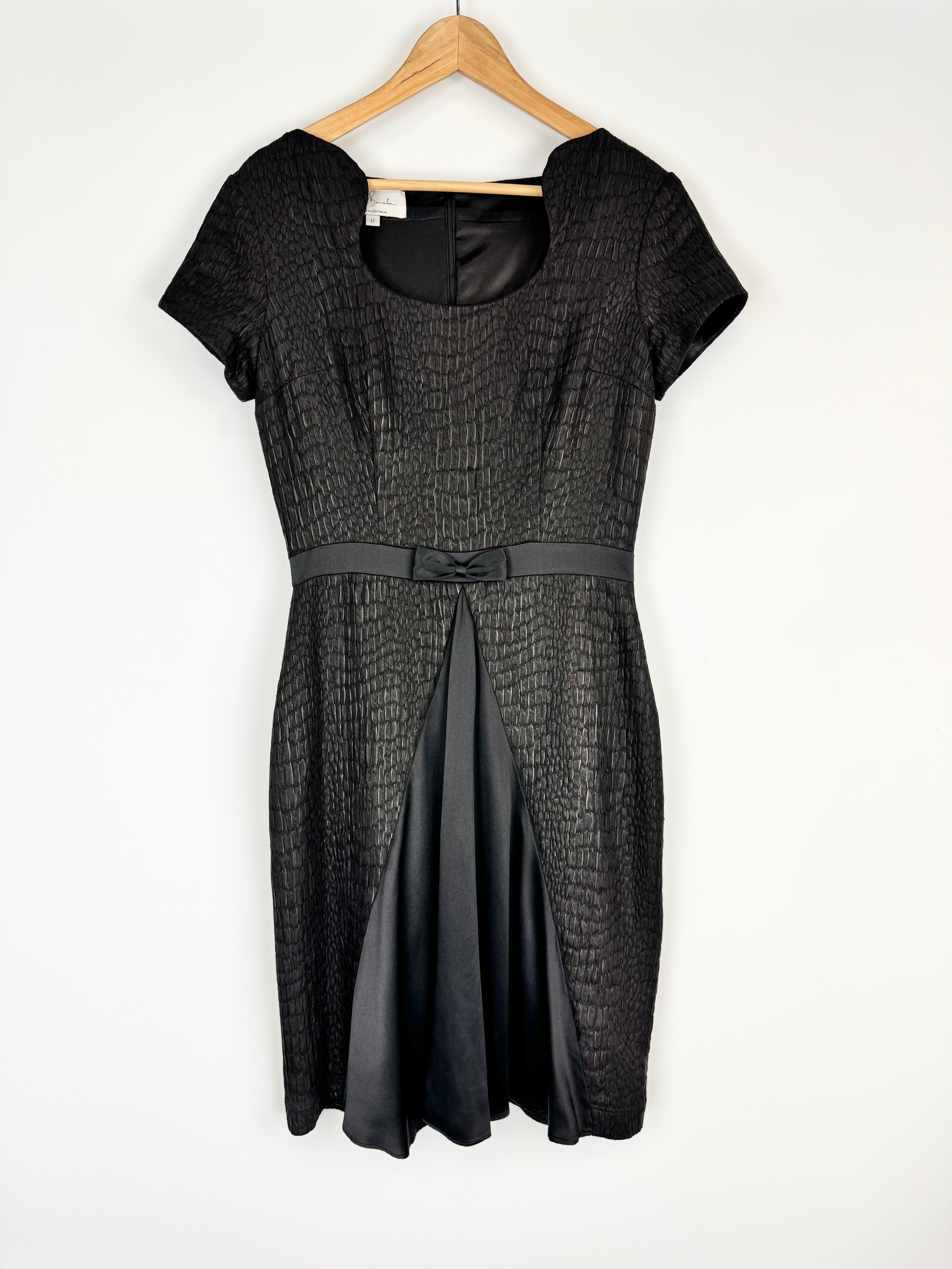 Black dress on a hanger against a white background