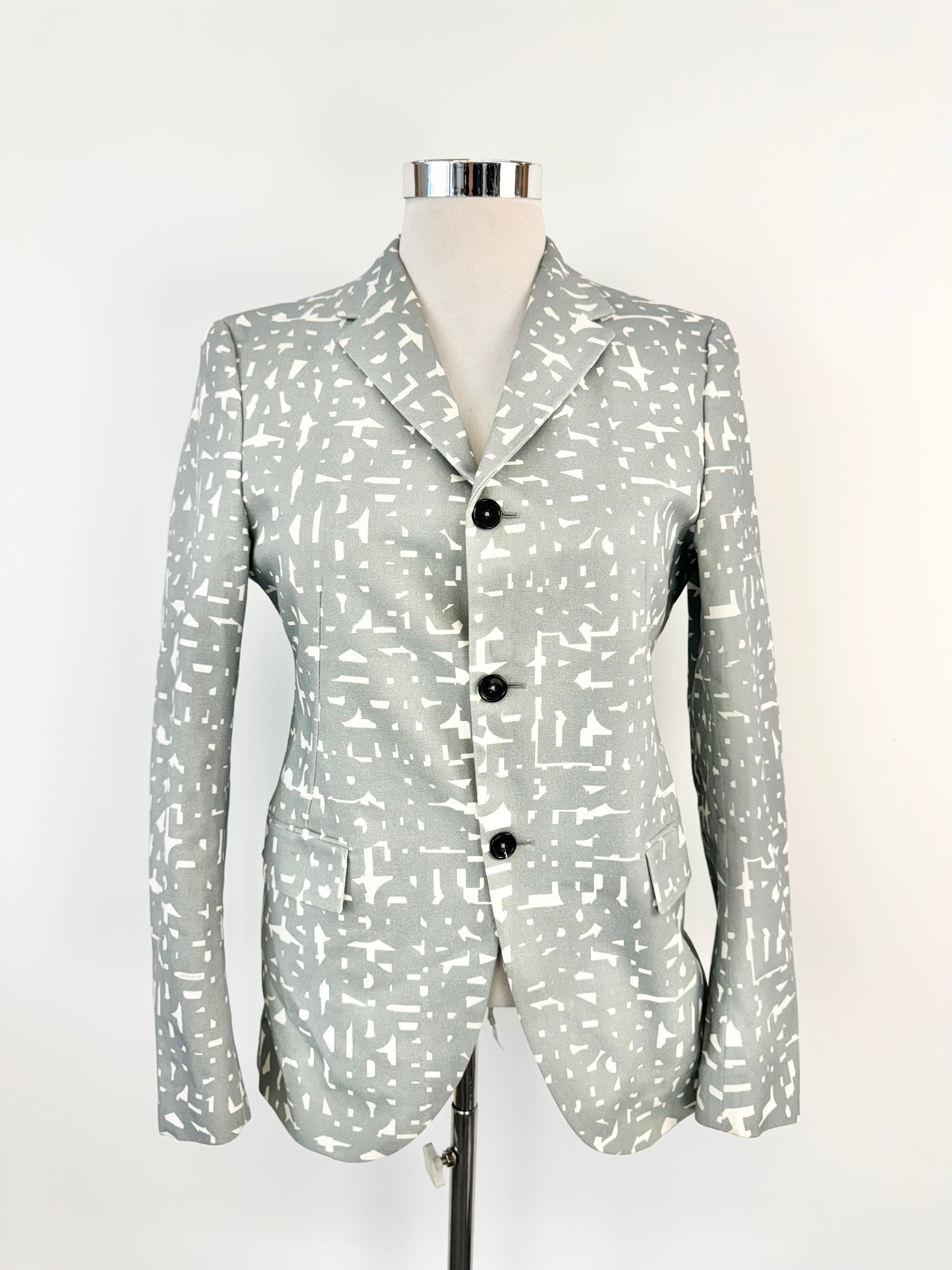 A Jil Sander grey text pattern blazer on a mannequin, featuring a tailored fit, collar, and three-button front.