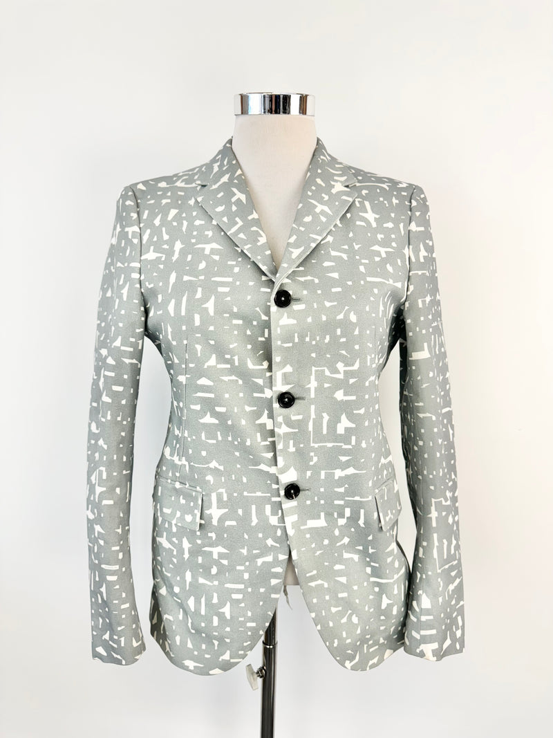 A Jil Sander grey text pattern blazer on a mannequin, featuring a tailored fit, collar, and three-button front.