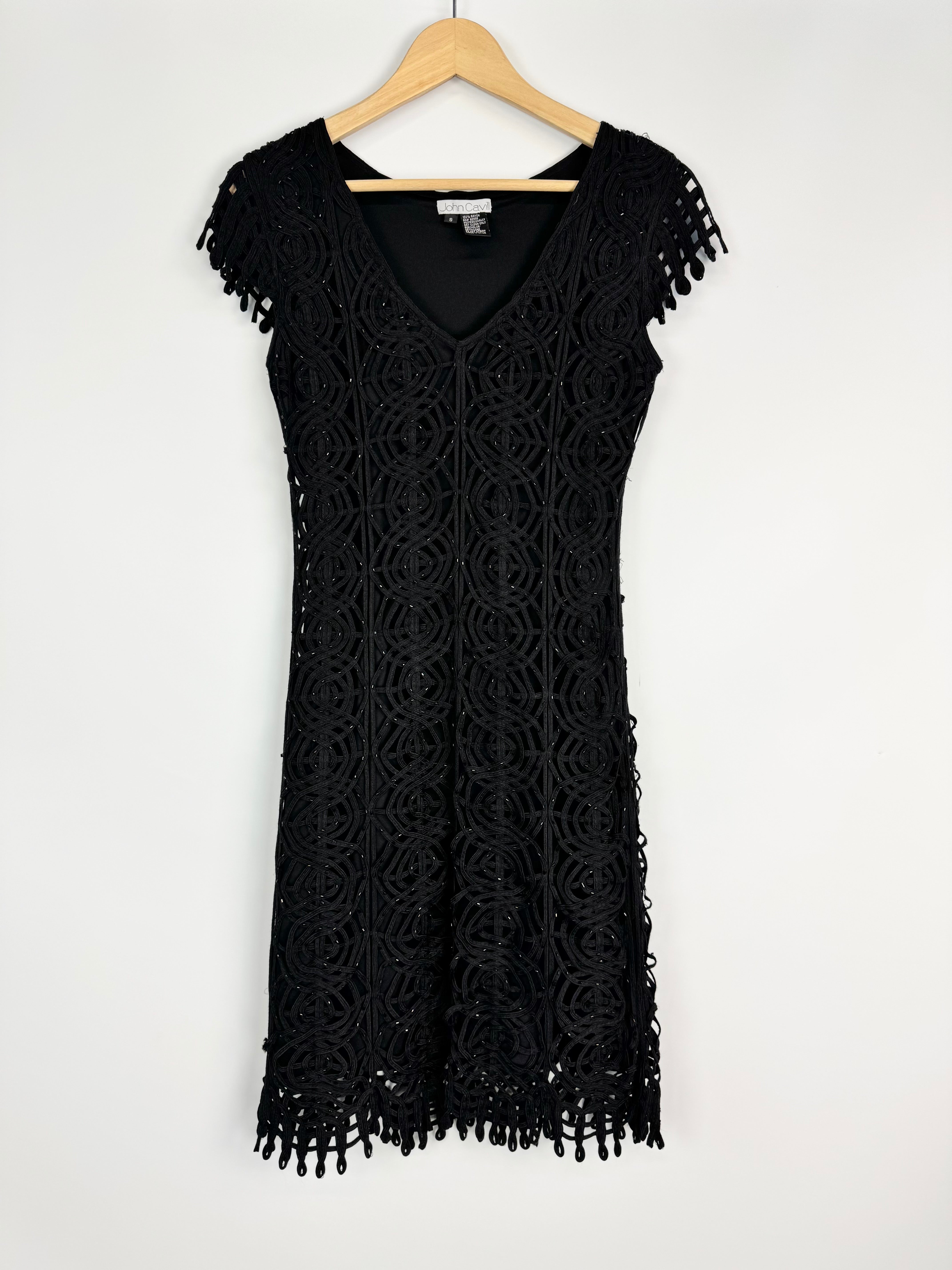 Black lace dress on a hanger against a white background