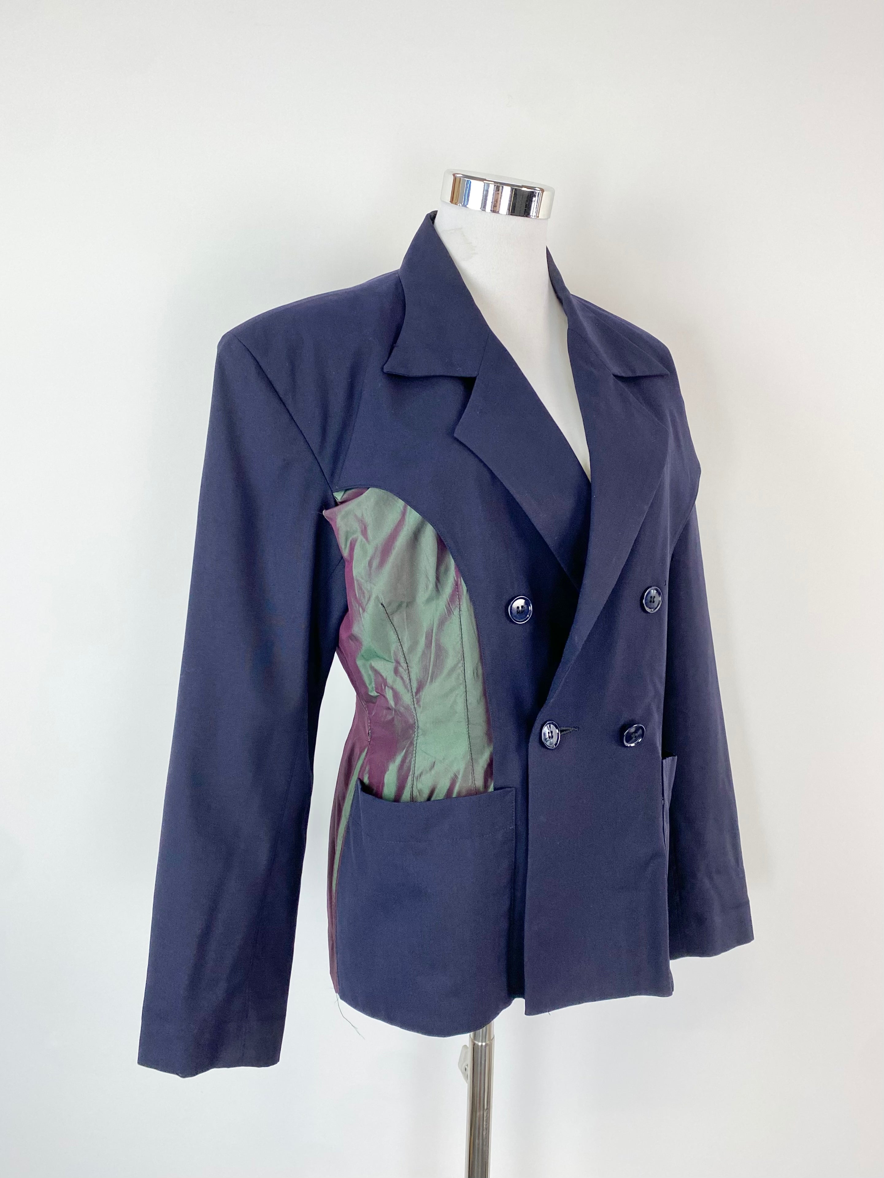 A blue and green shot silk and wool blazer with a mandarin collar, displayed on a mannequin with visible signs of wear.