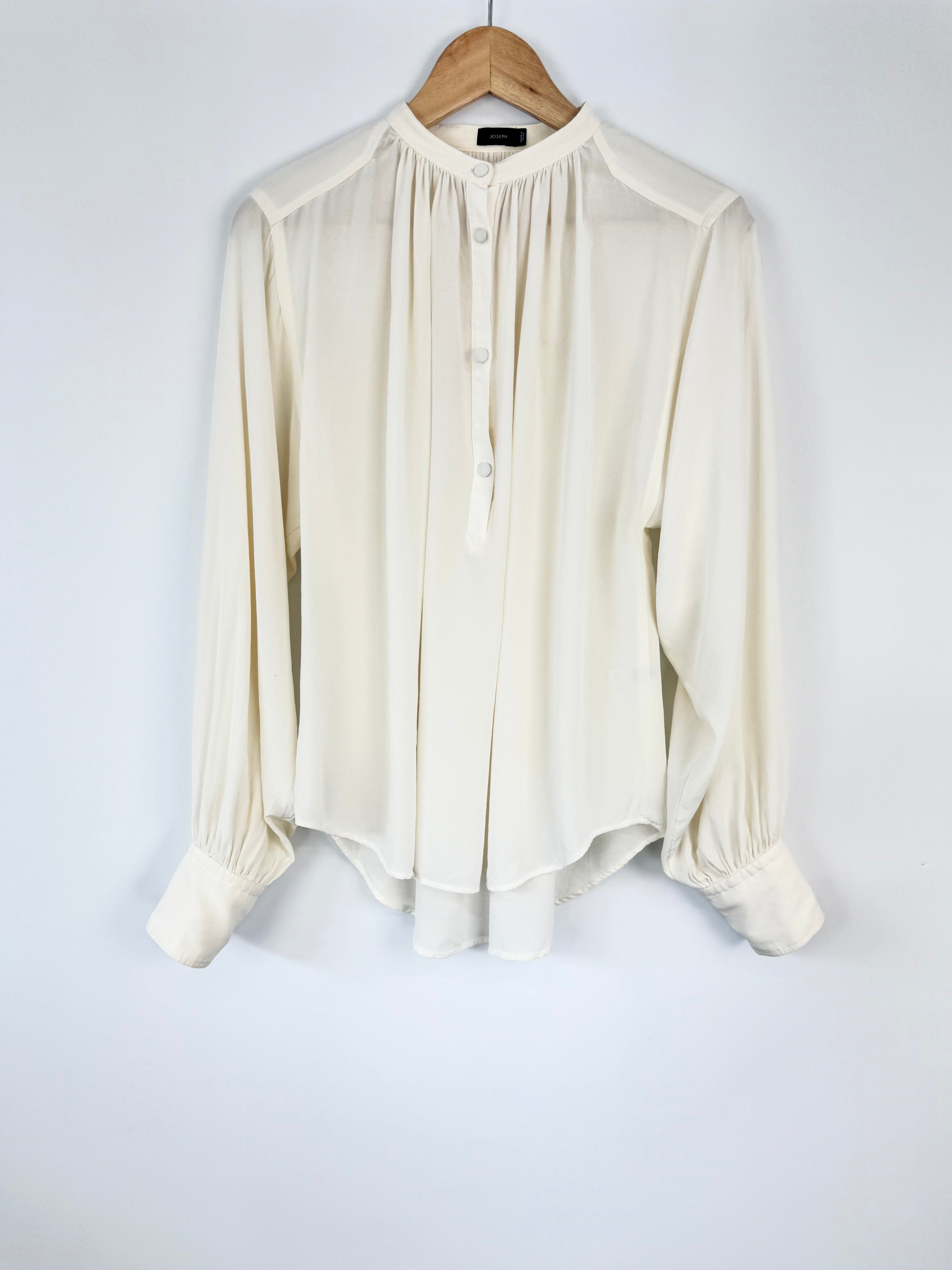 White blouse on a wooden hanger against a white background