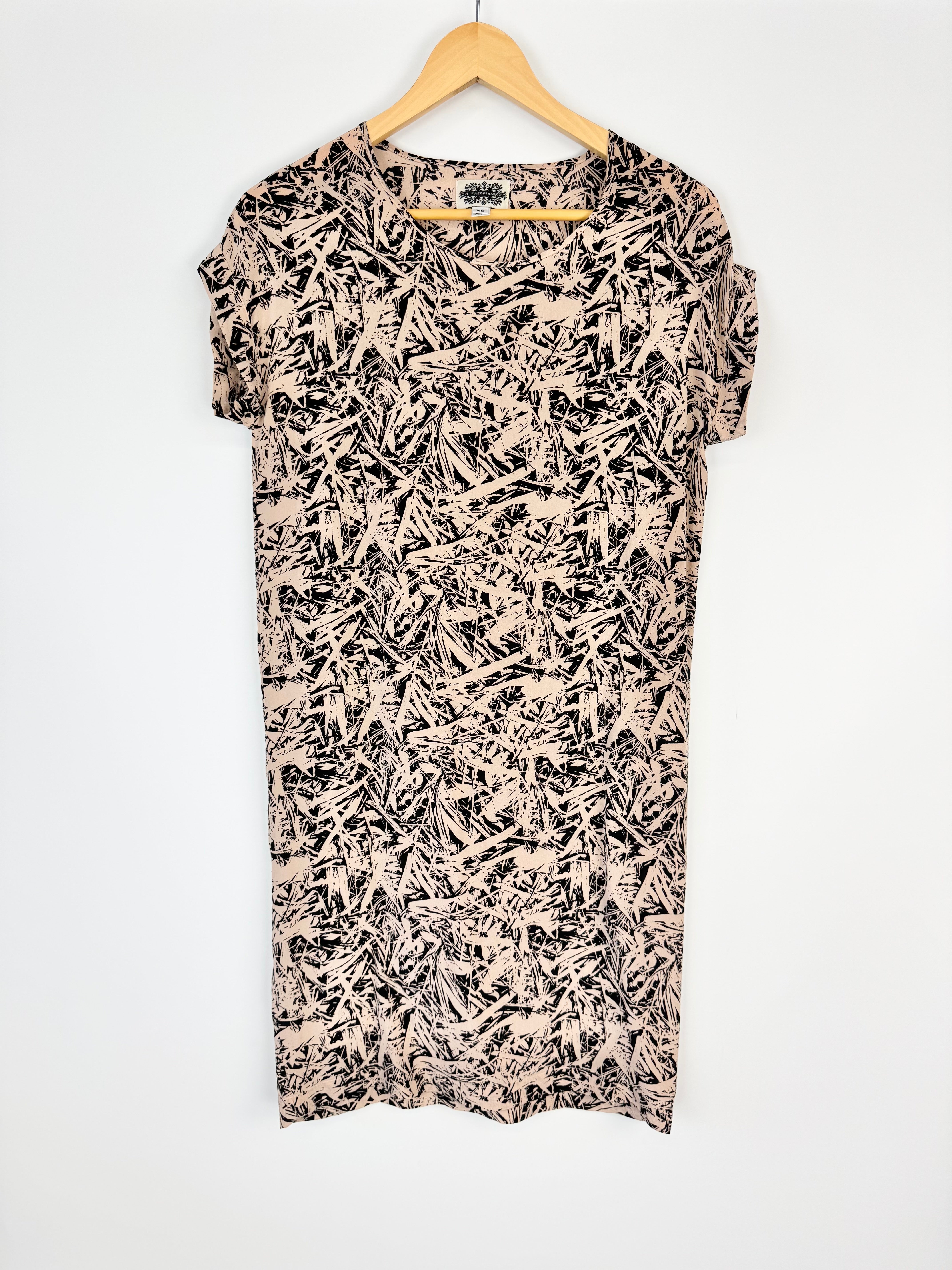 Short-sleeve dress with a black and beige abstract pattern on a hanger against a white background