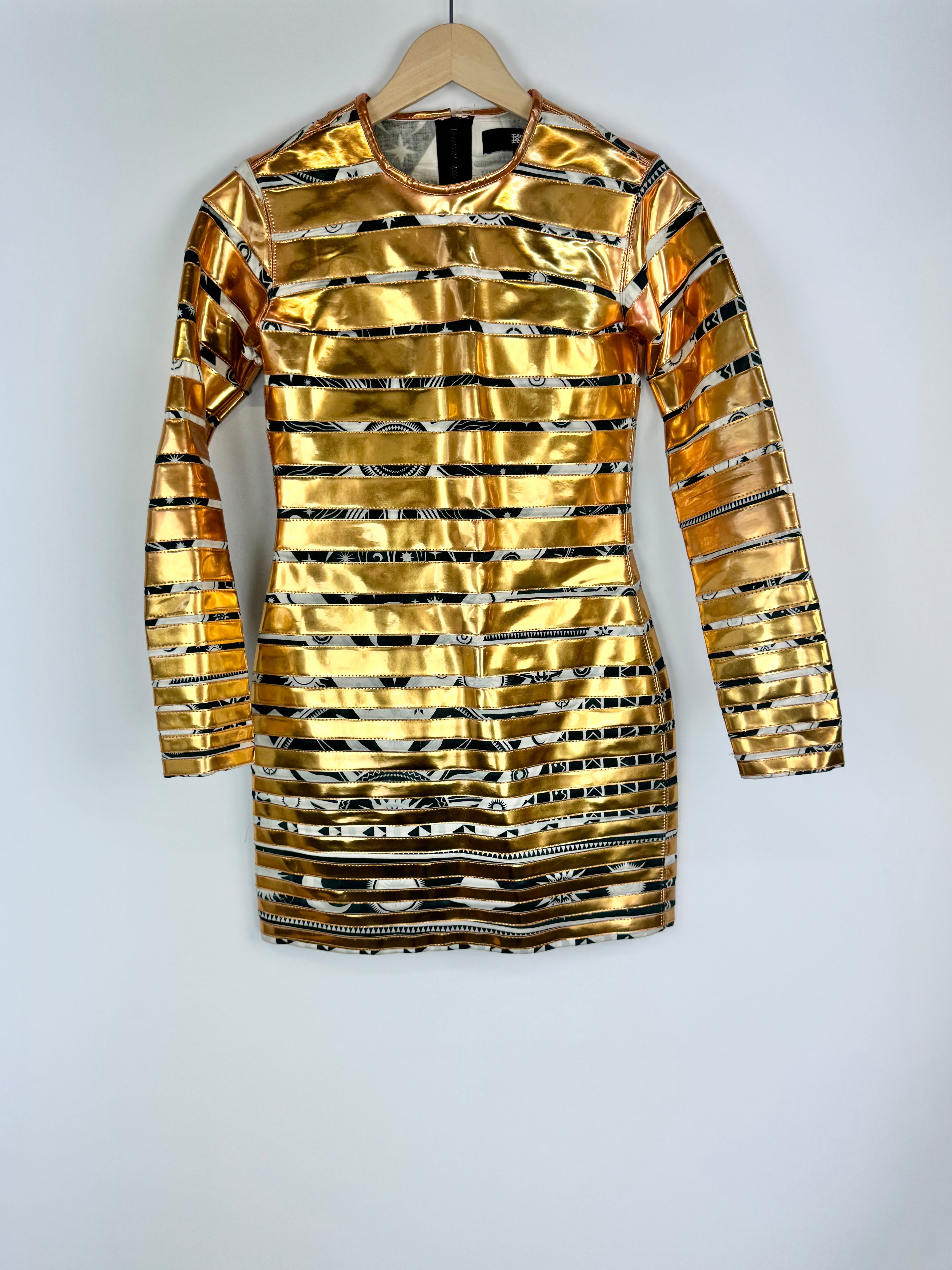 Gold and black striped dress on a hanger against a white background