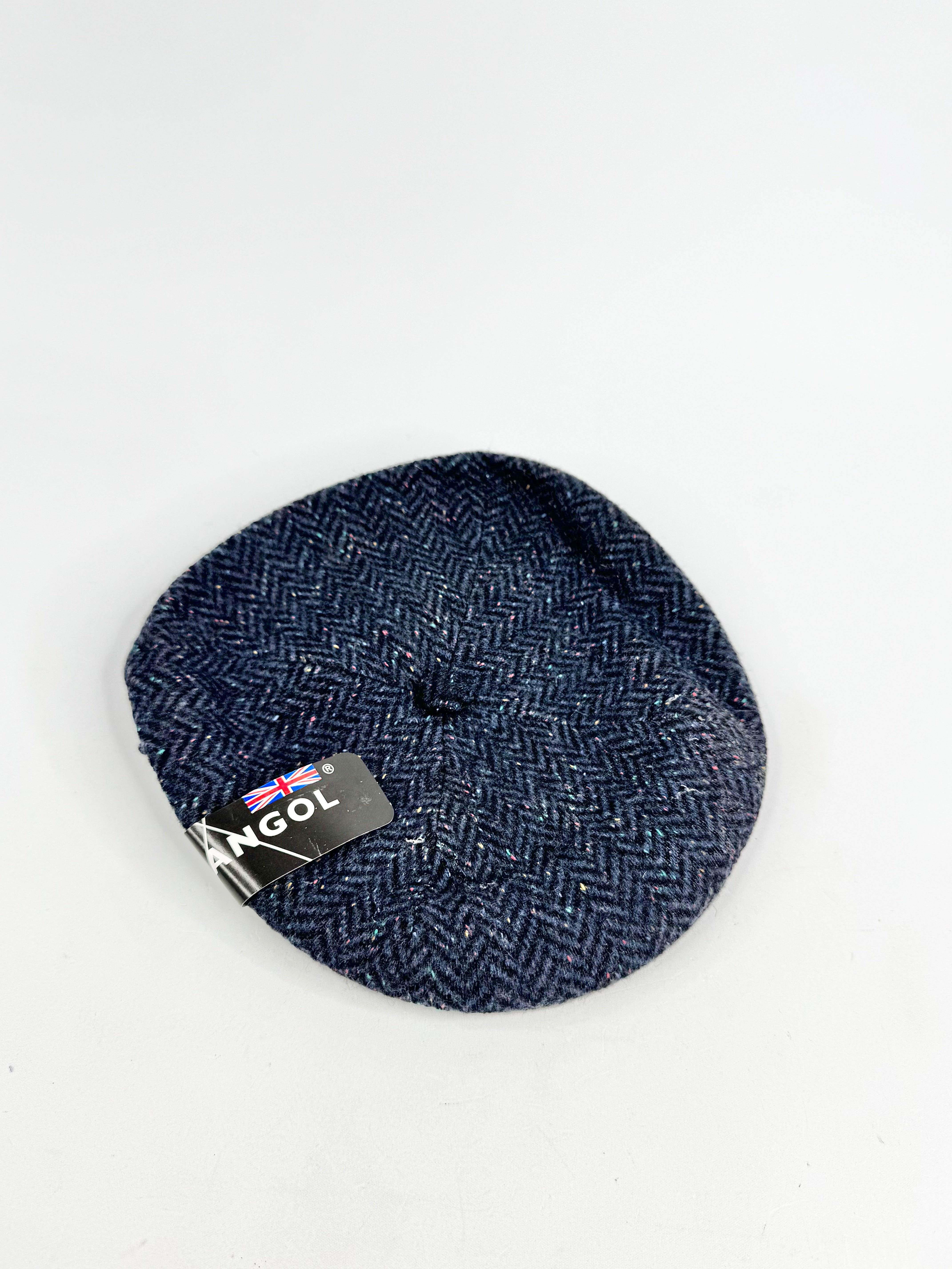 Blue herringbone patterned beret with a label on a white background