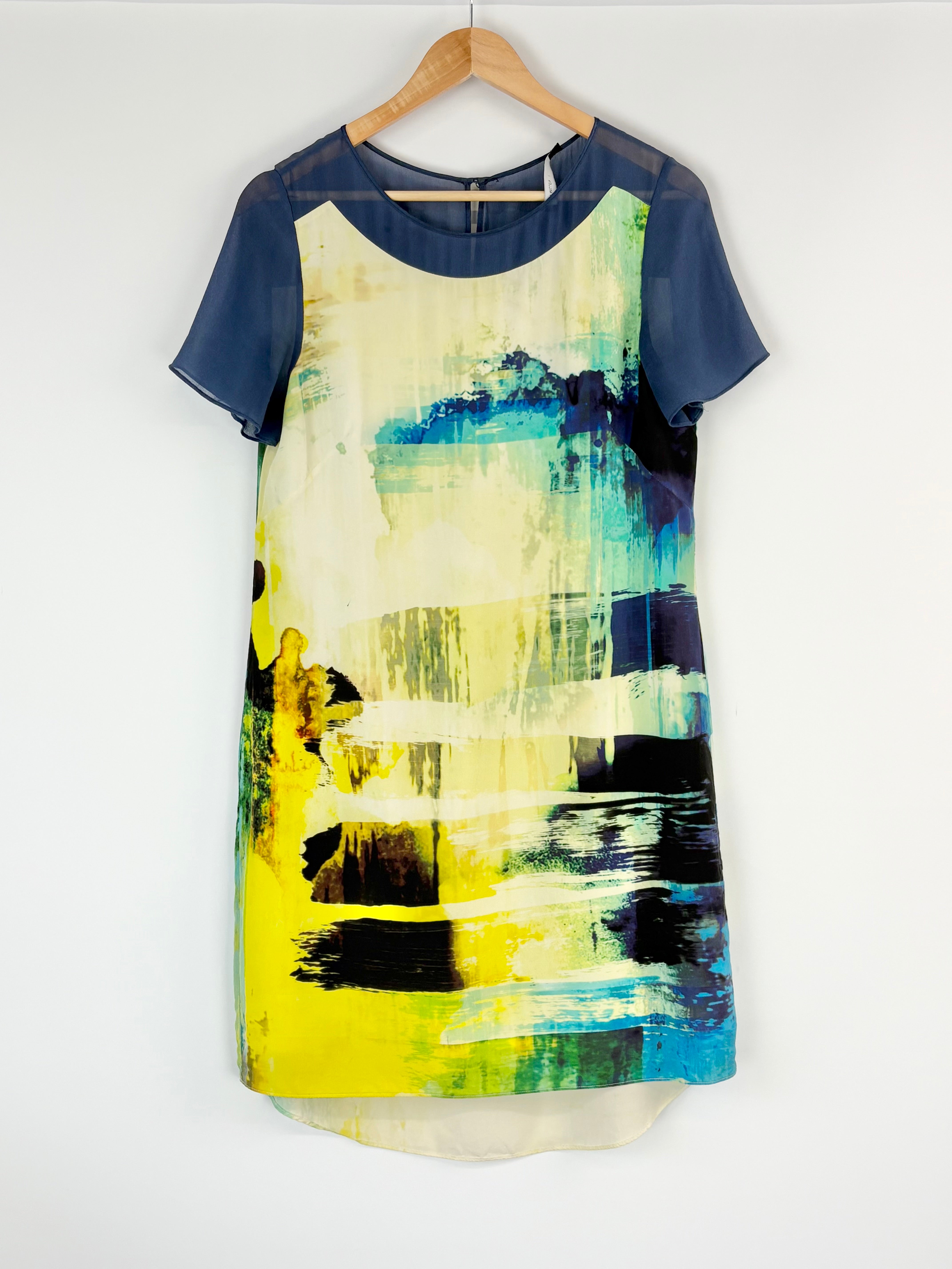 Dress with abstract art design on a hanger against a white background