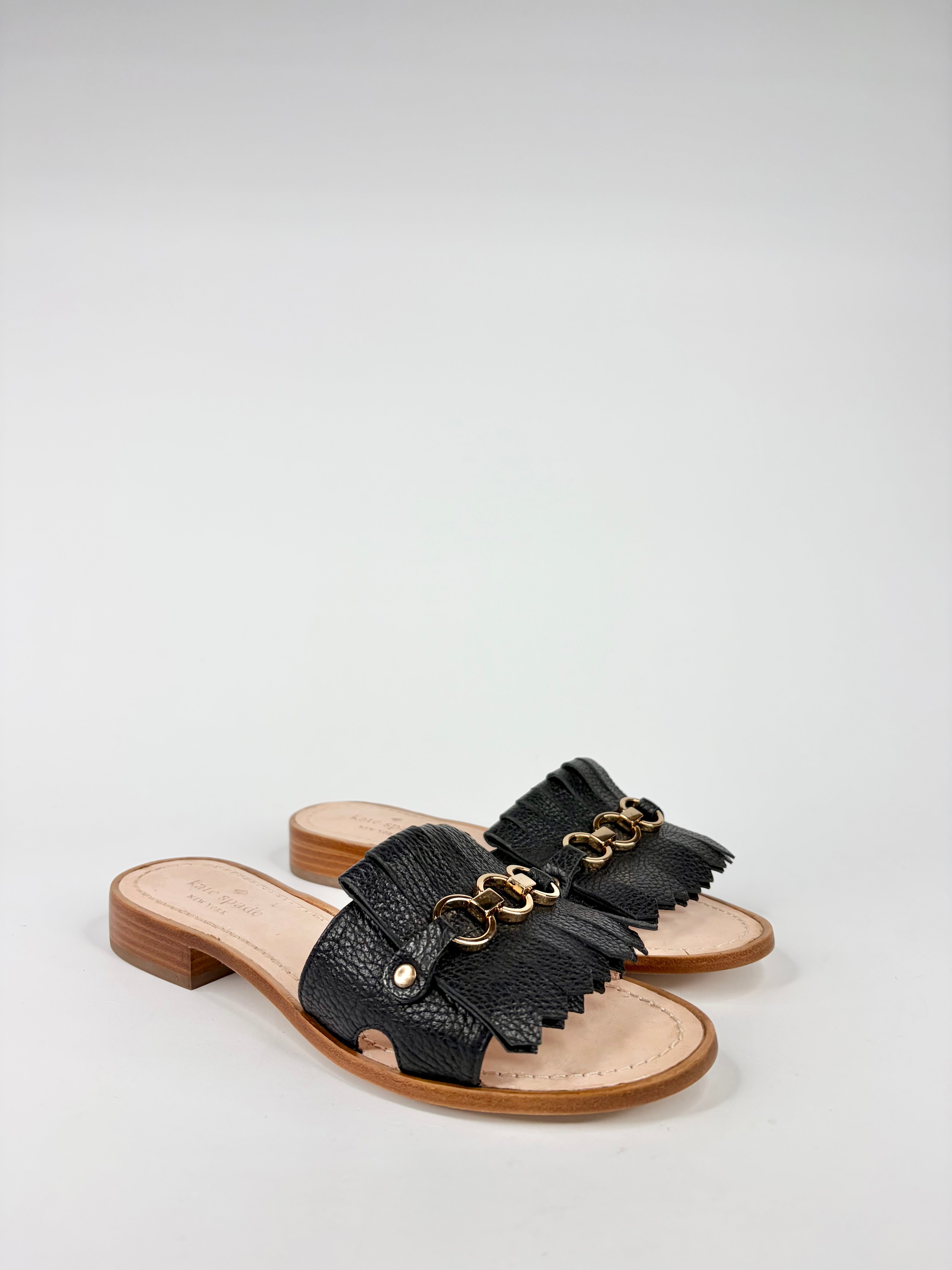 Black sandals with gold chain detail on a white background