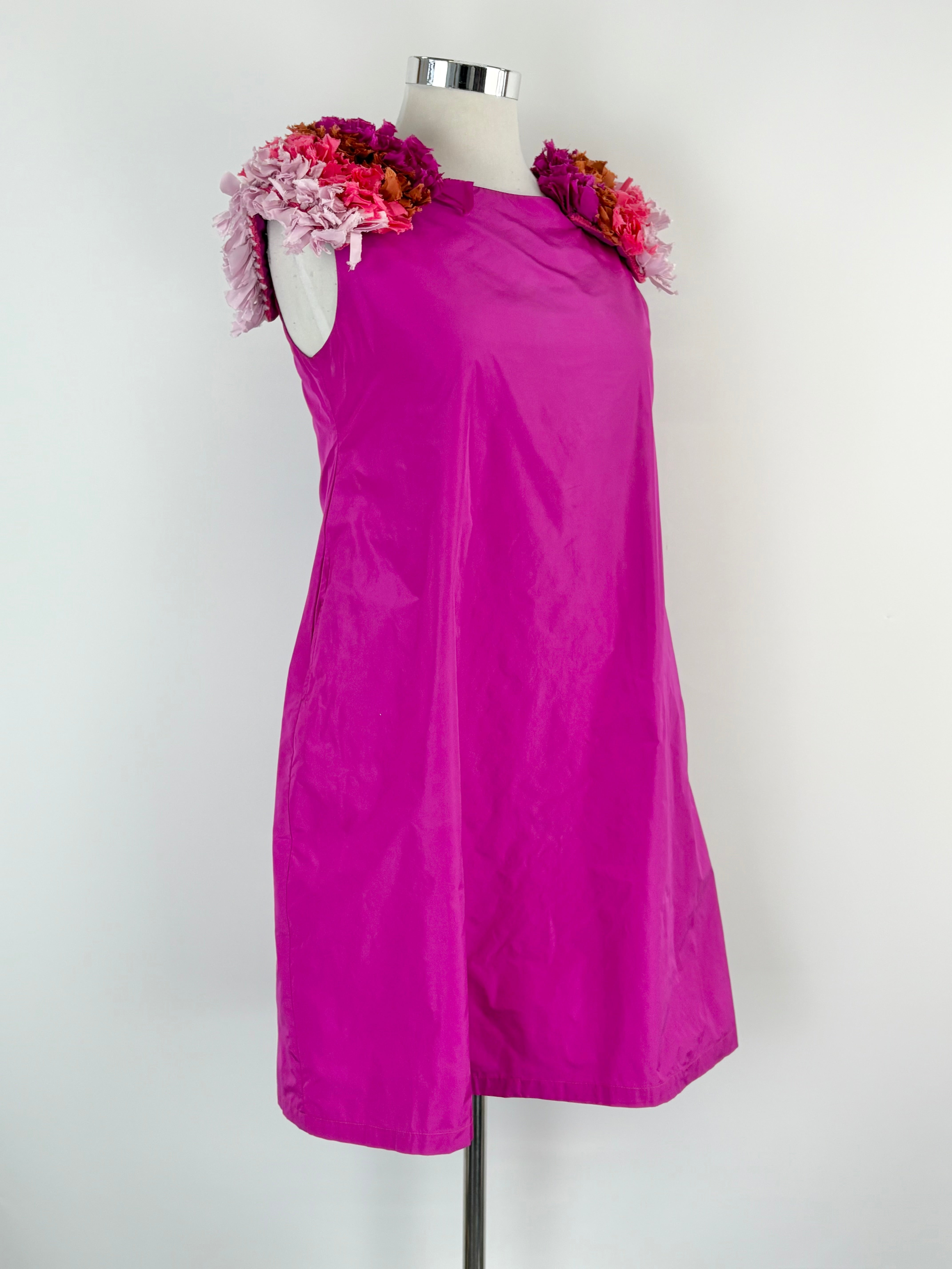 Fuchsia dress on a mannequin with floral accessories against a white background