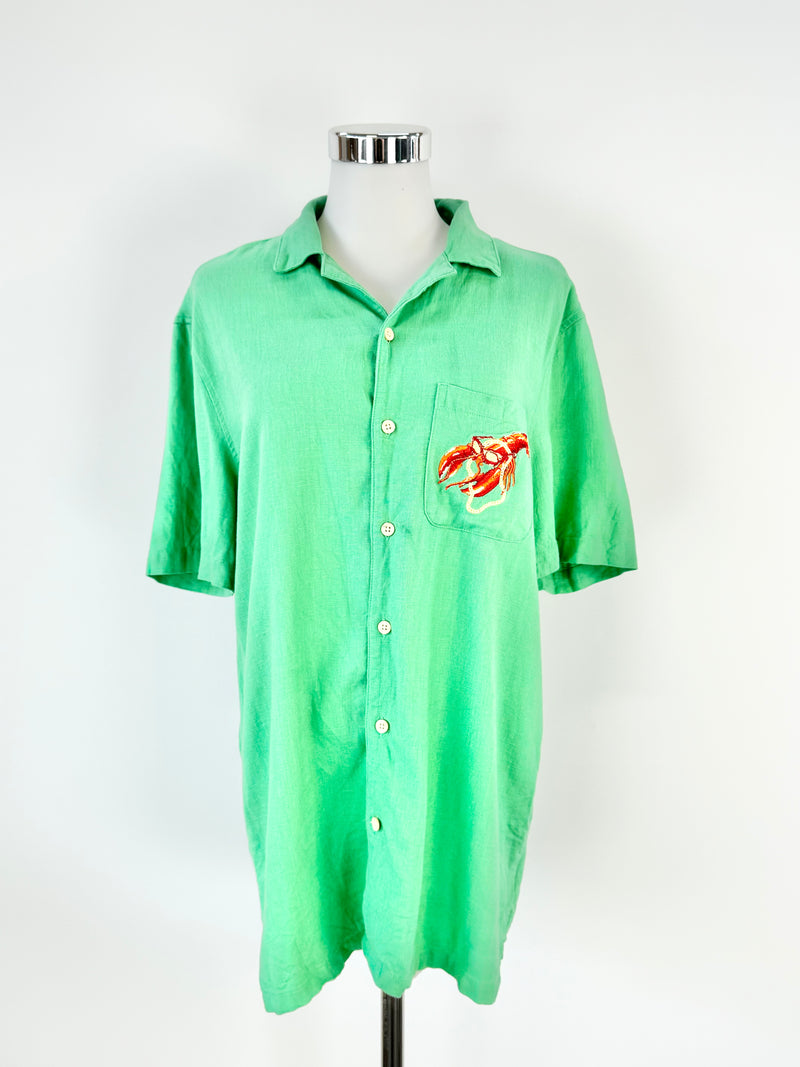 A green short-sleeved shirt displayed on a mannequin, featuring a small red and yellow lobster graphic on the front.