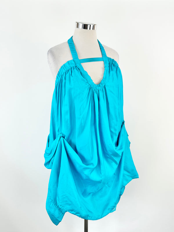 Aqua blue silk dress displayed on a mannequin, featuring a halterneck, cut-out bust section, and pleated design.