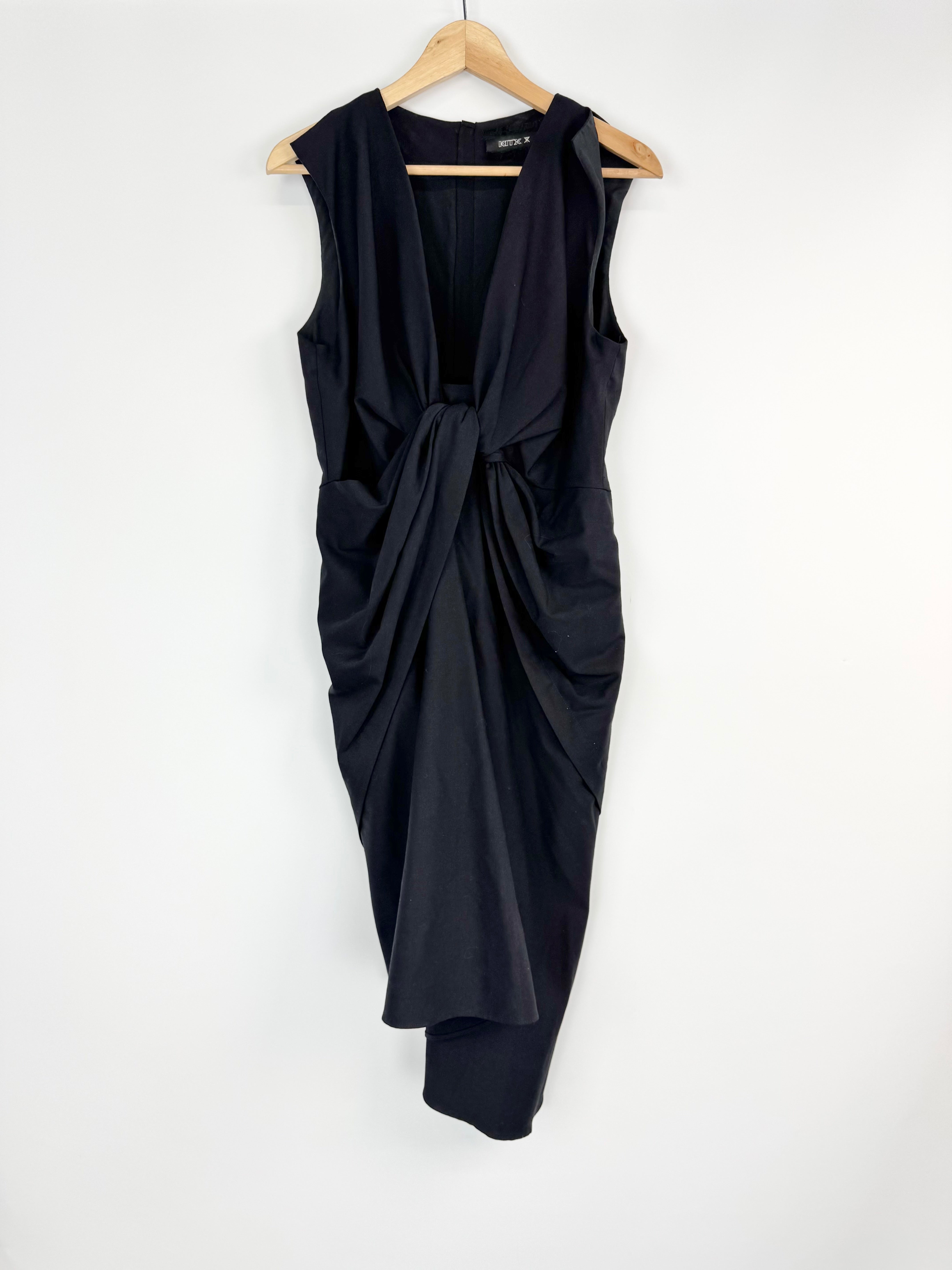 Black sleeveless dress with a draped design on a hanger against a white background