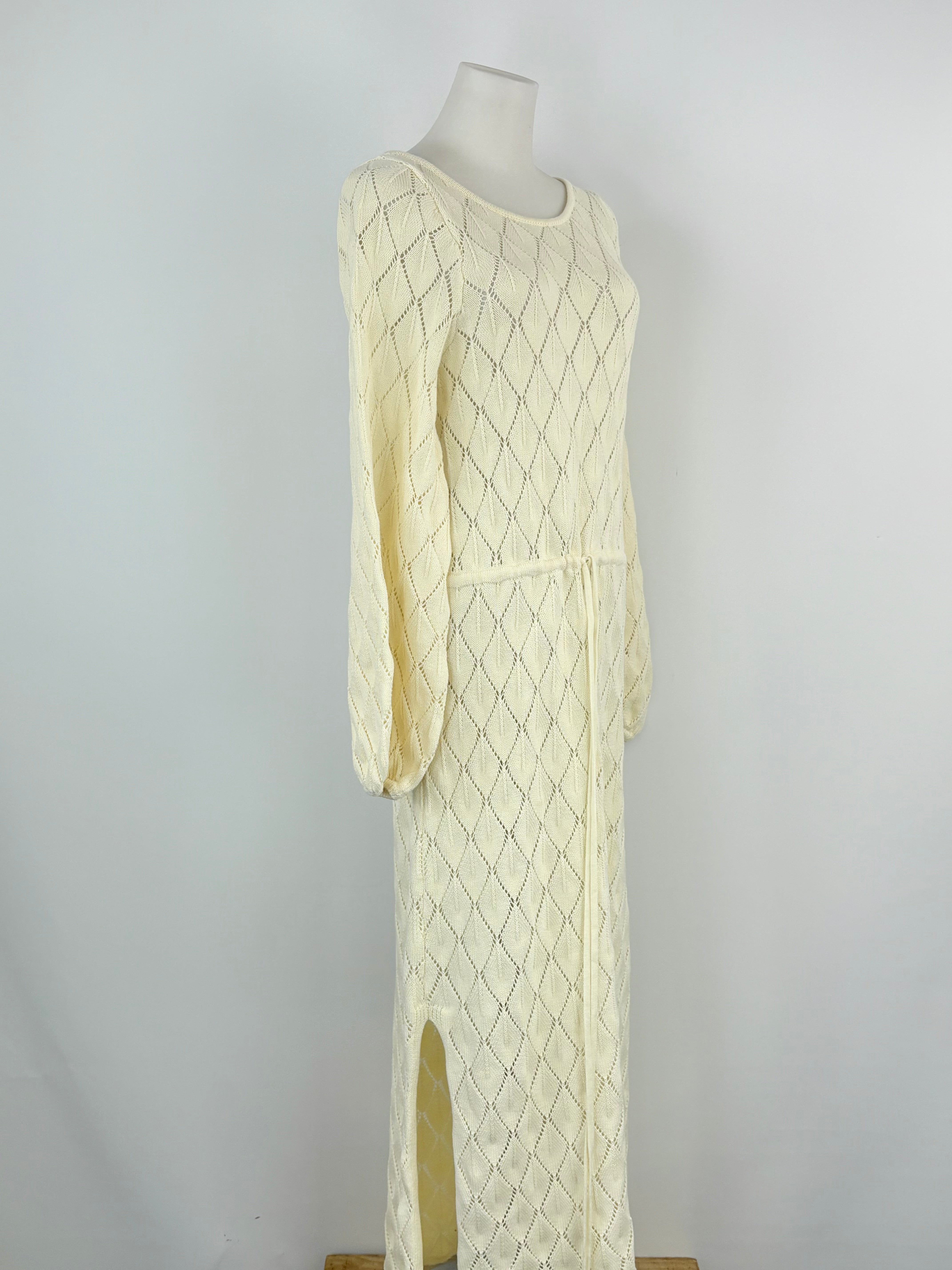 Cream-colored cable knit dress on a mannequin against a plain background