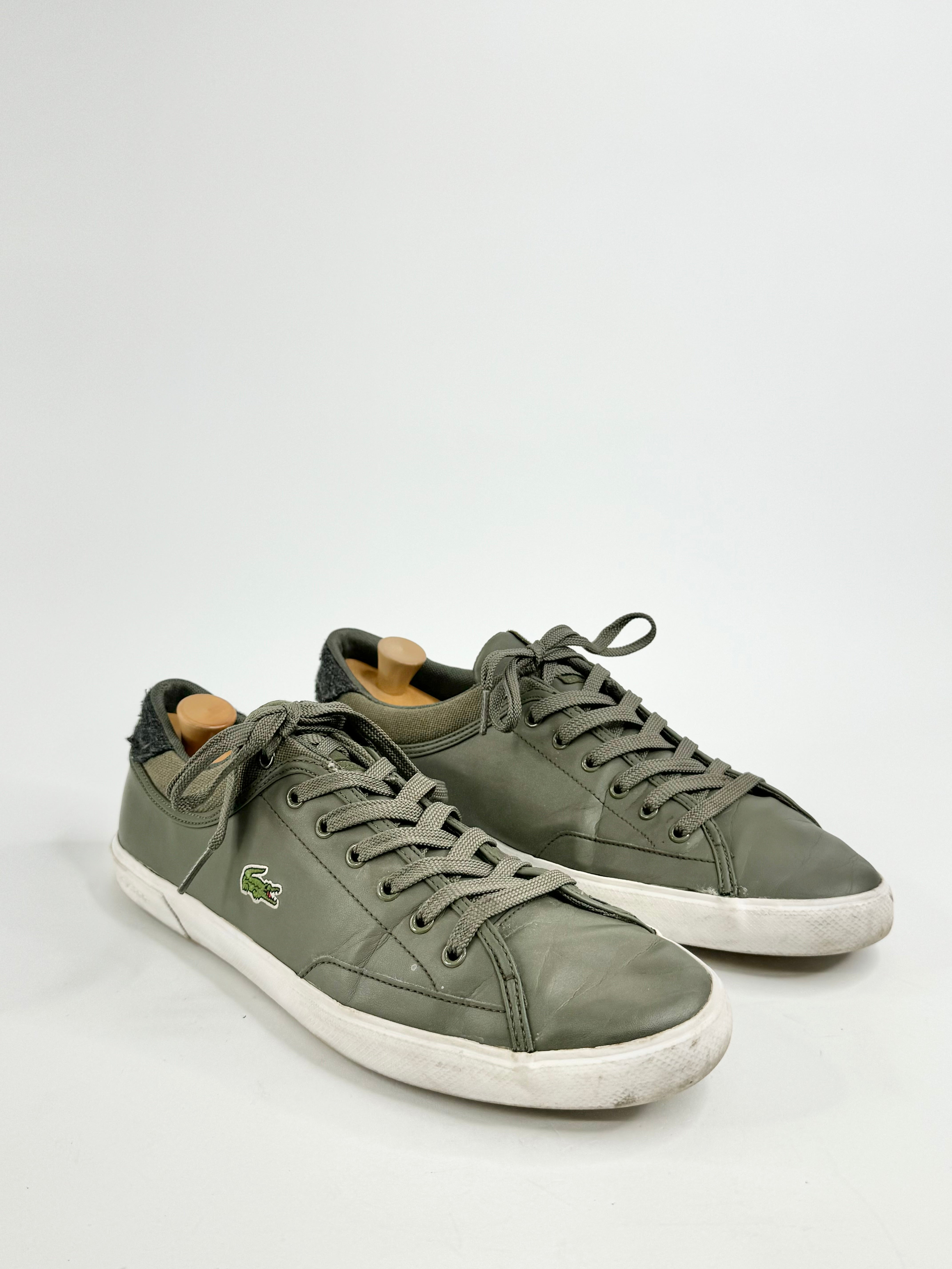 A pair of Lacoste moss green lace-up shoes with visible wear on the soles.