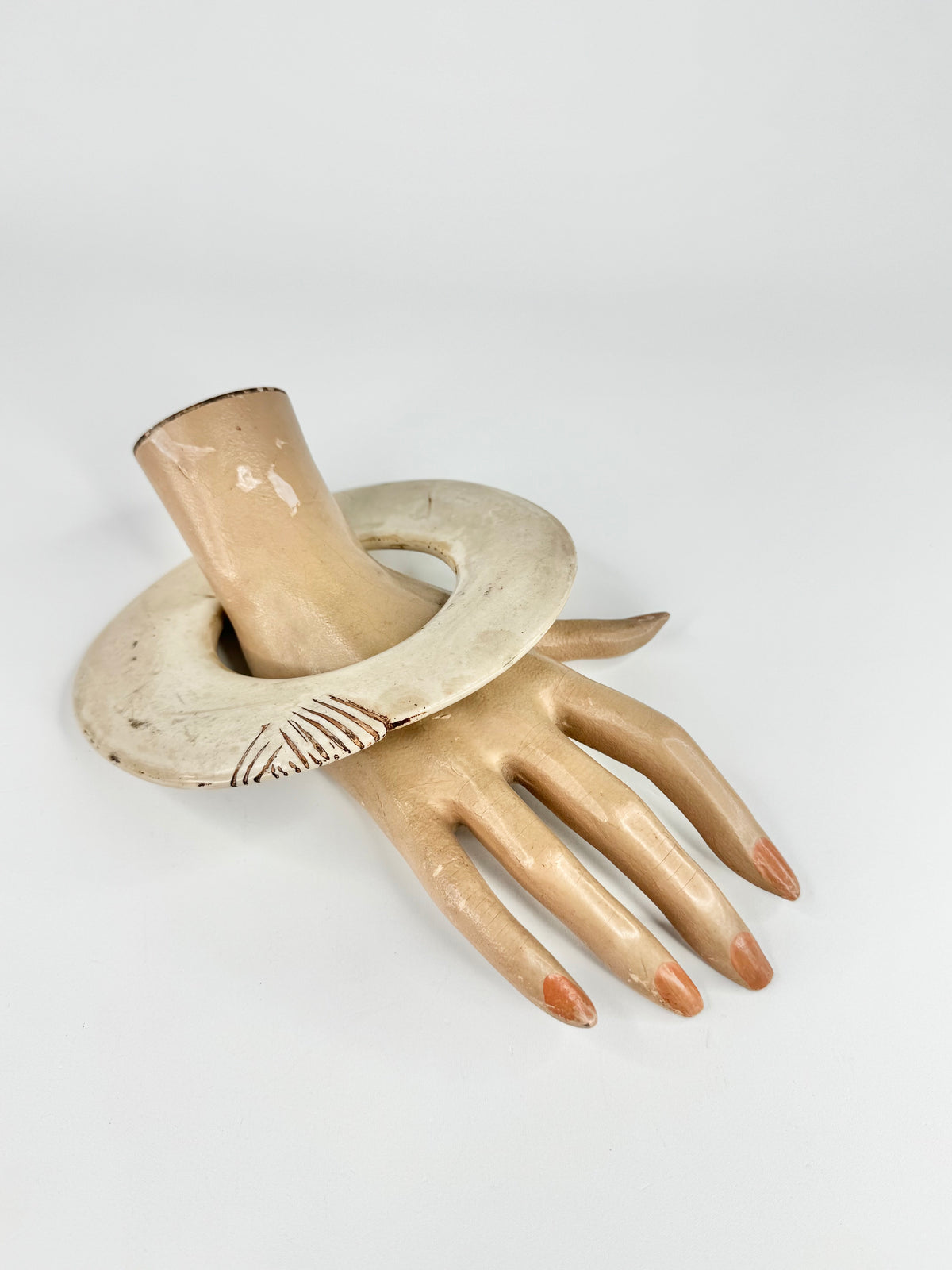 Decorative item resembling a hand with a cylindrical object on a light gray background
