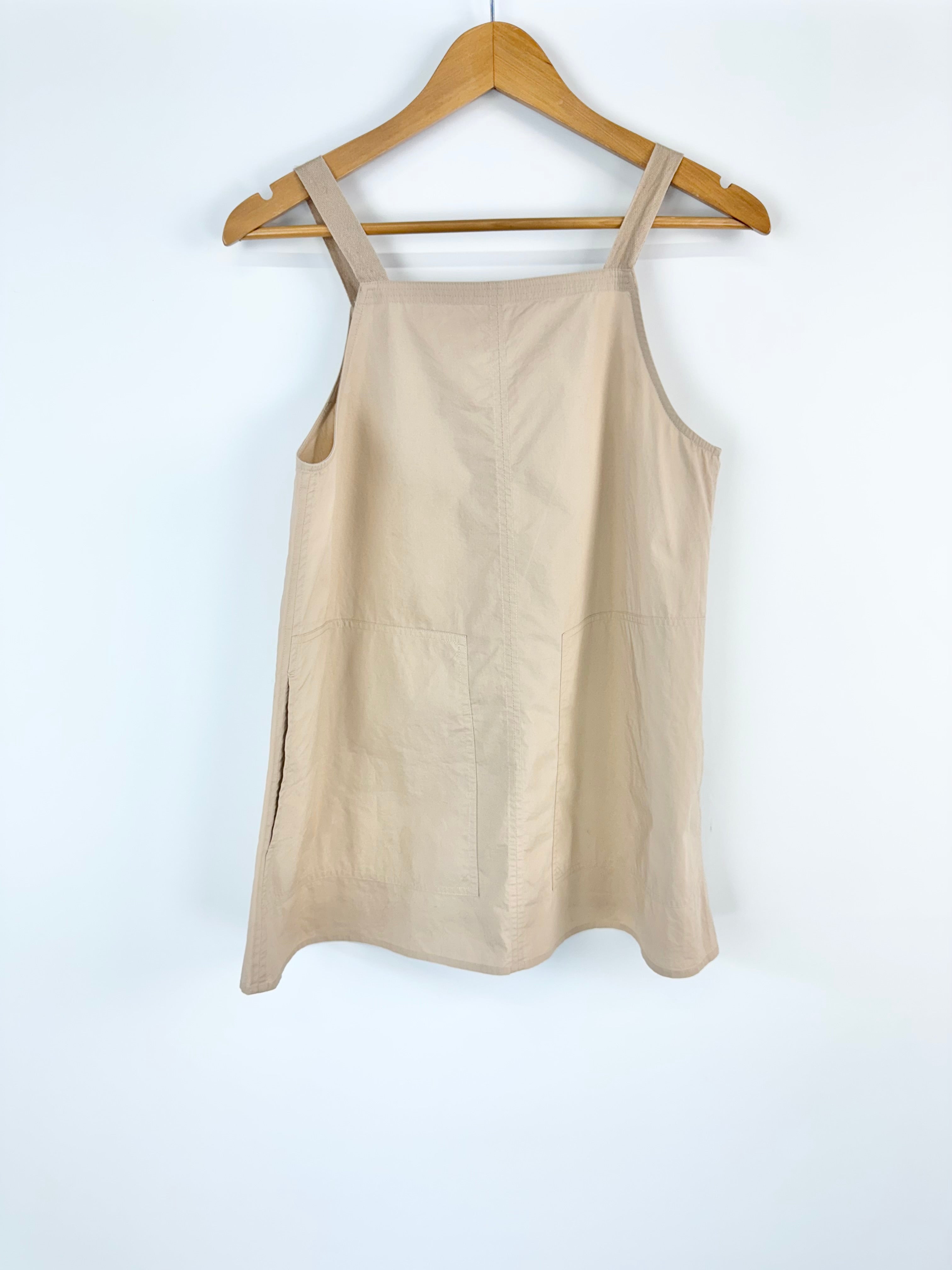 Beige tank top on a wooden hanger against a white background