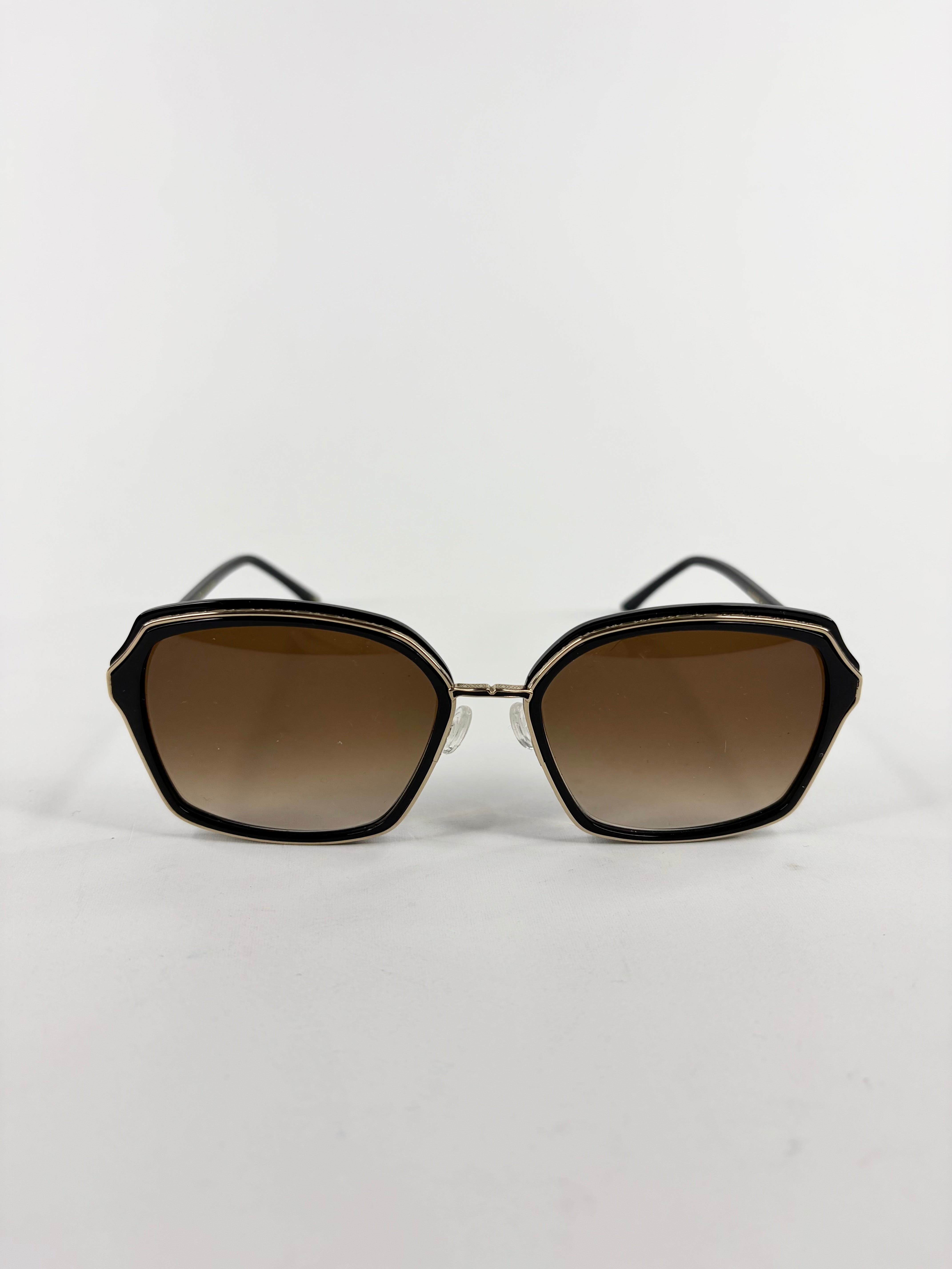 Sunglasses with black frames and brown gradient lenses on a white background