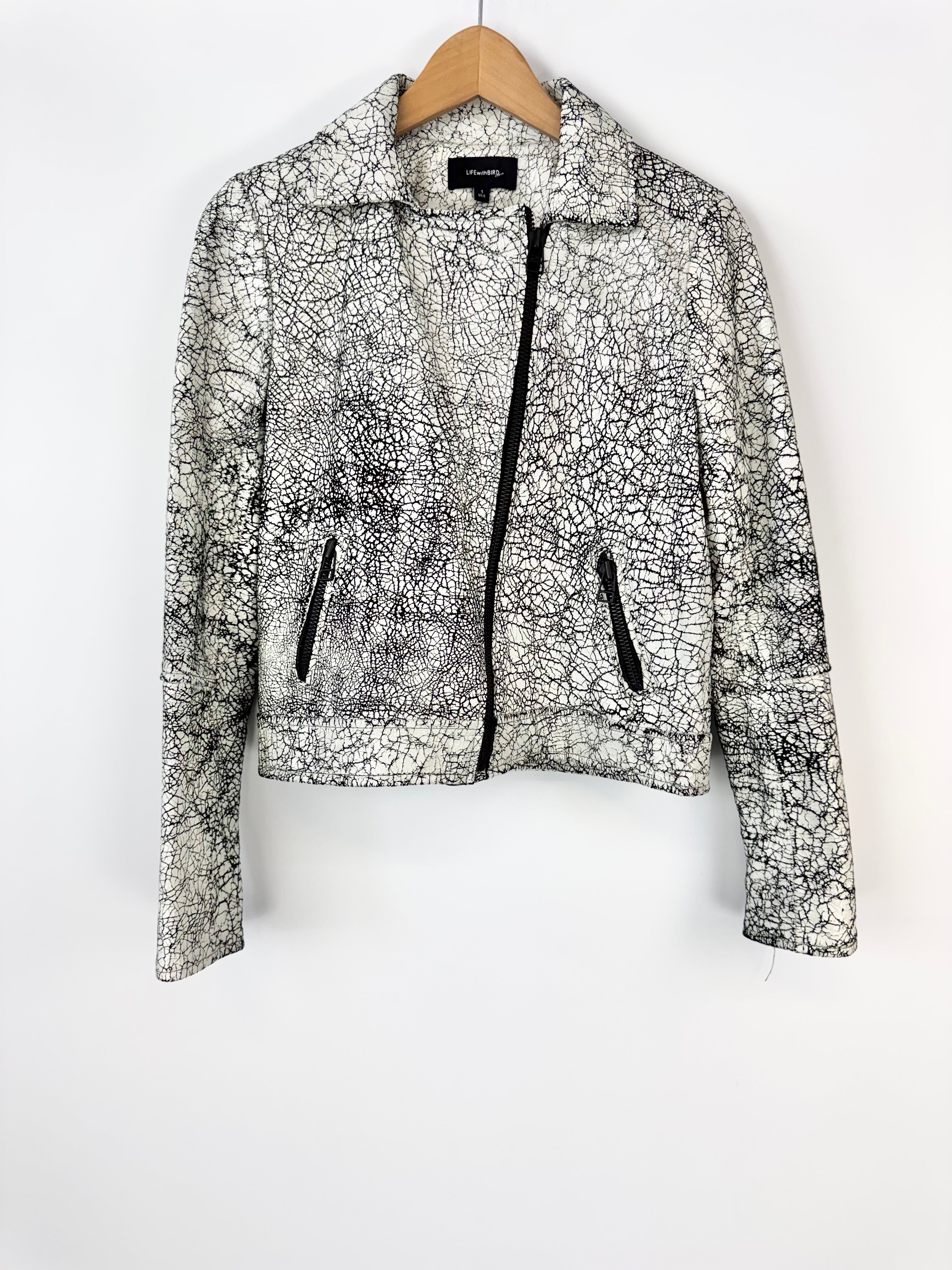 Black and white patterned jacket on a hanger against a white background