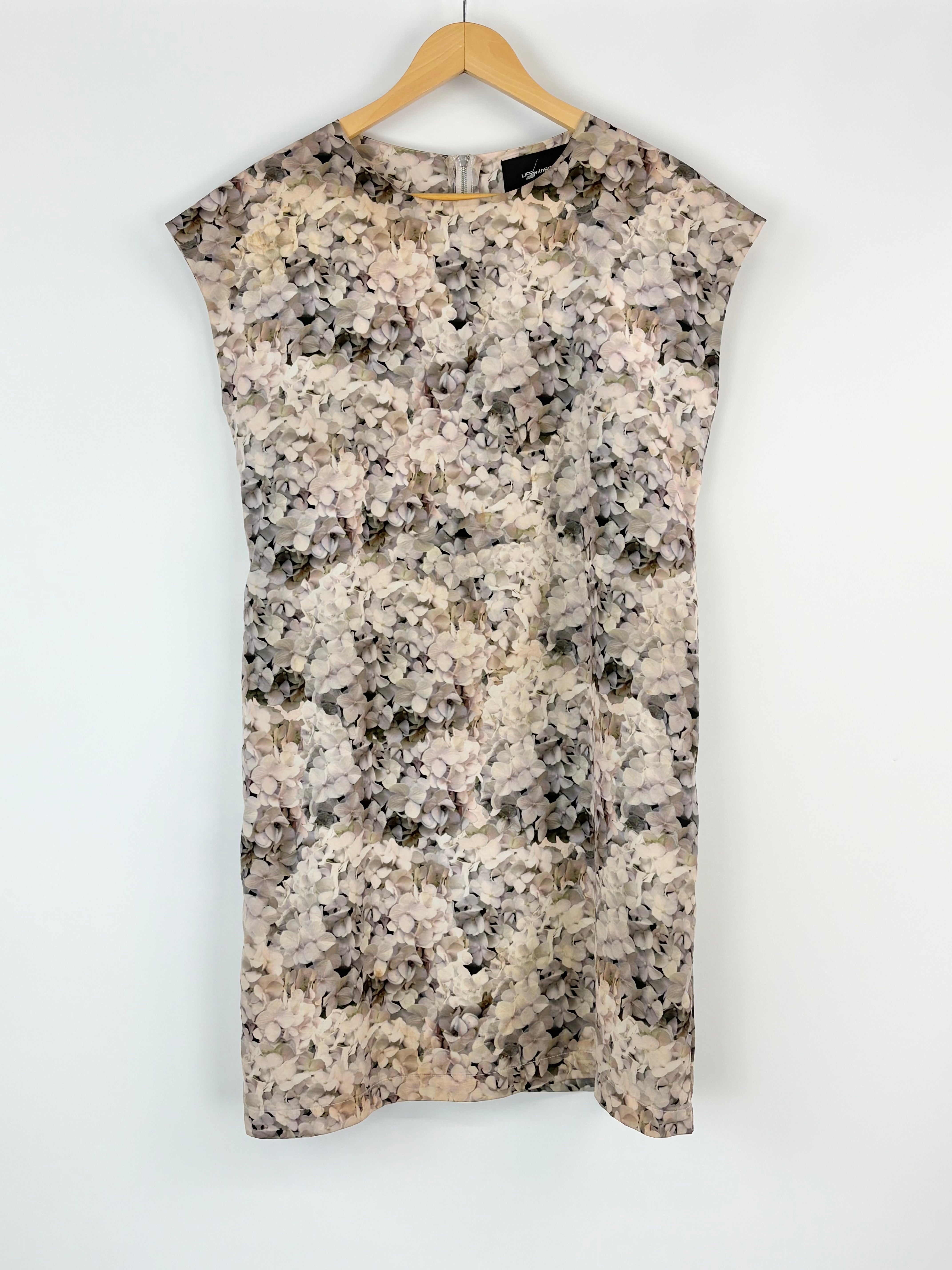 Floral patterned sleeveless top on a hanger against a white background