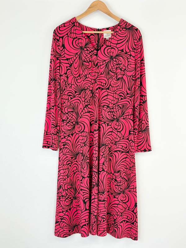 Pink dress with black abstract pattern on a hanger against a white background