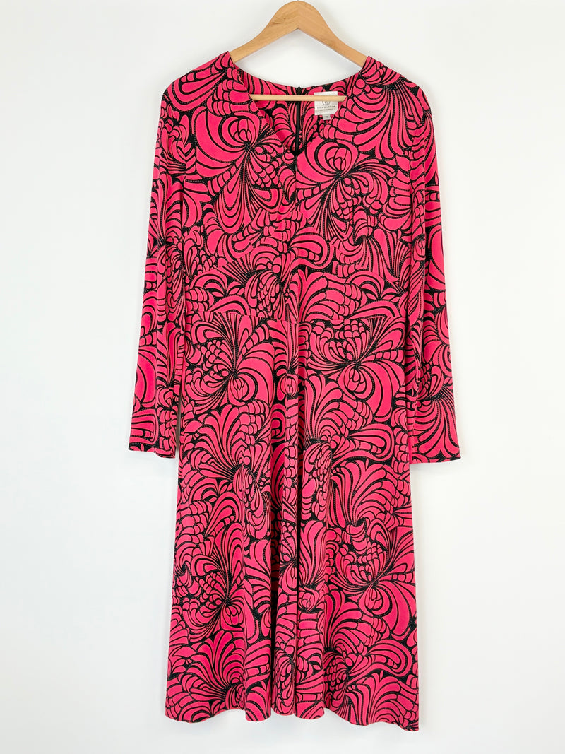 Pink dress with black abstract pattern on a hanger against a white background