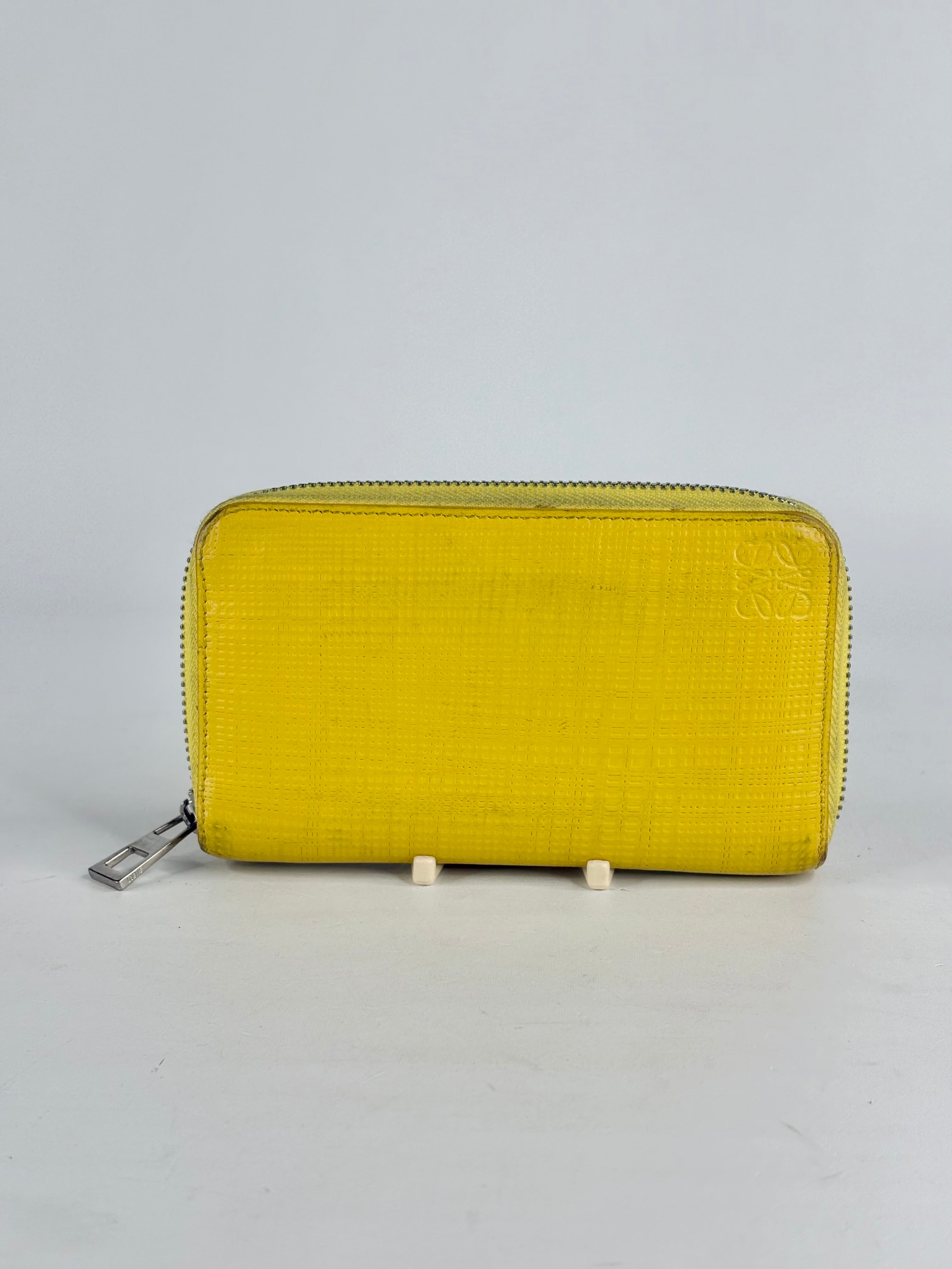 Yellow wallet with a silver zipper on a light gray background