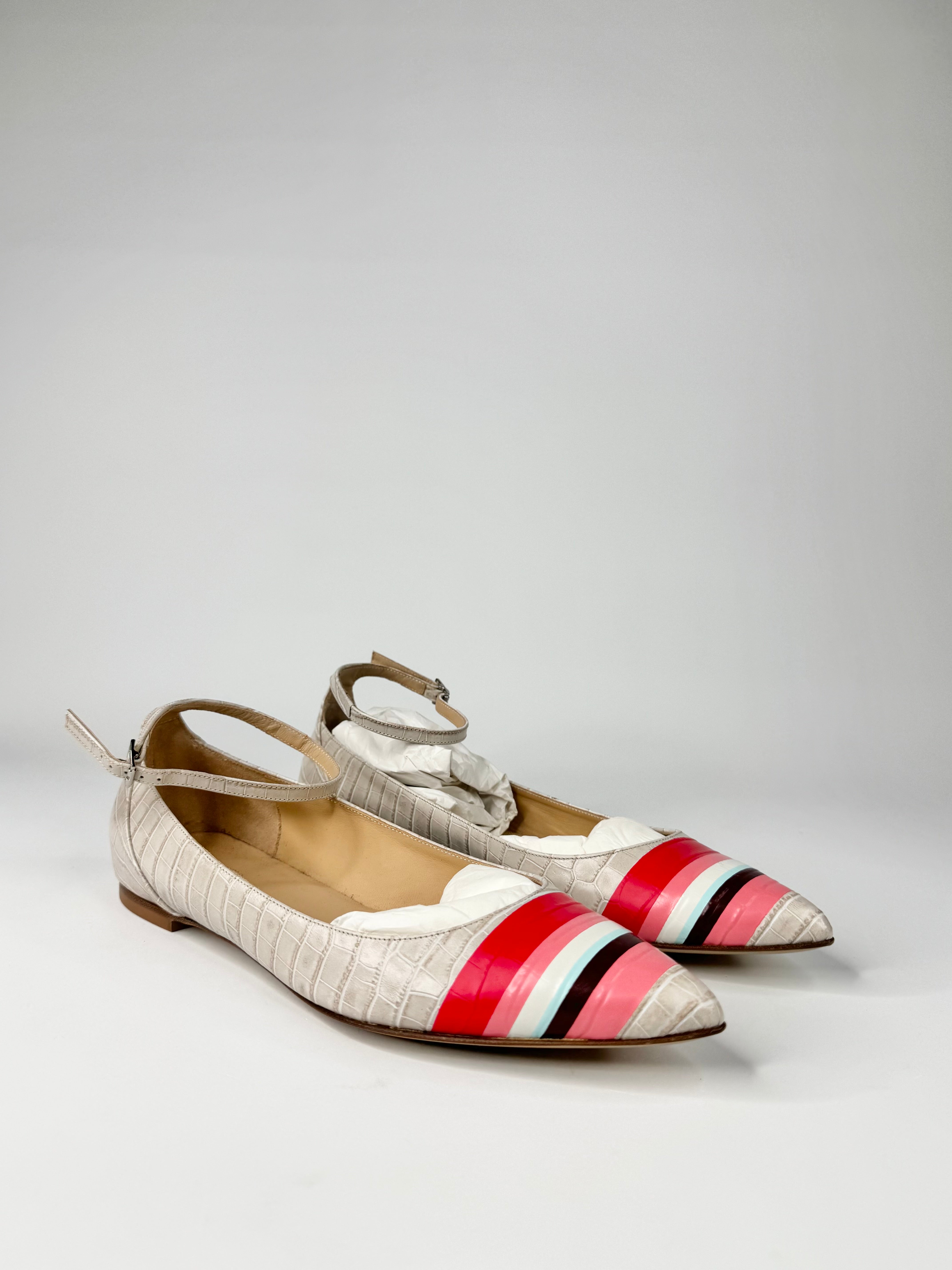 Pair of pointed-toe shoes with colorful striped design on a light gray background