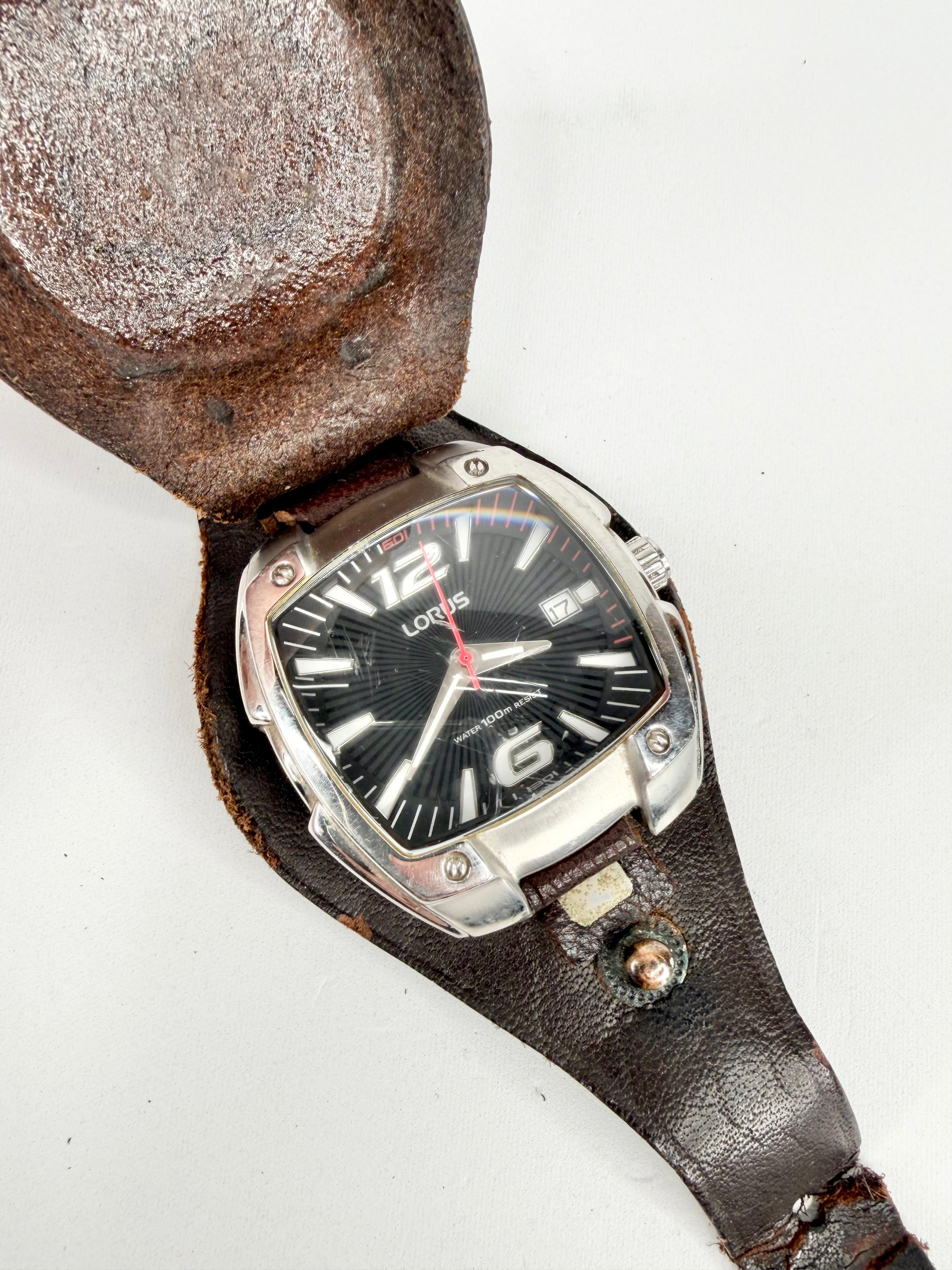 Vintage watch with a black face and silver case in a leather holder on a white background