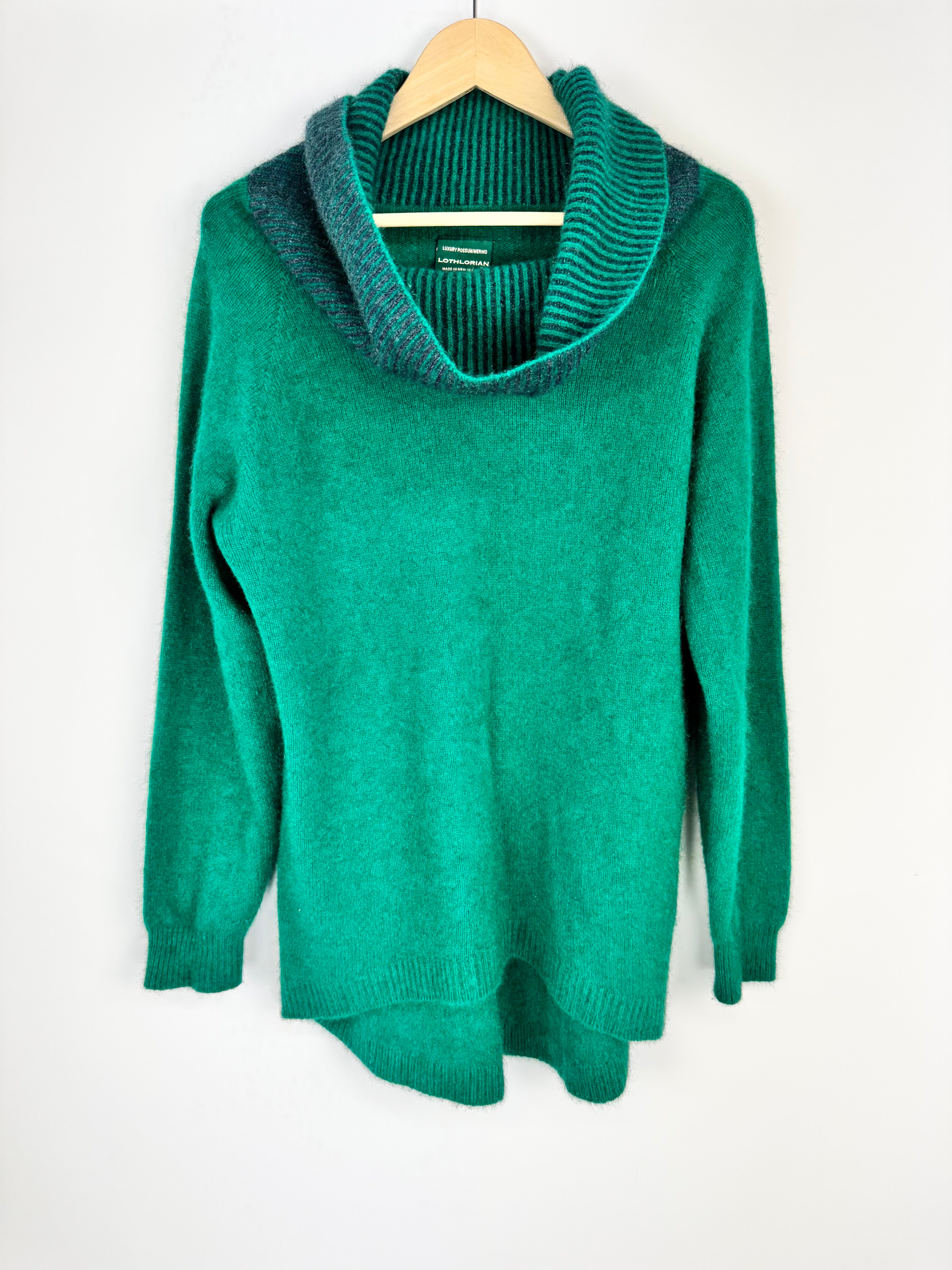 Green sweater on a hanger against a white background