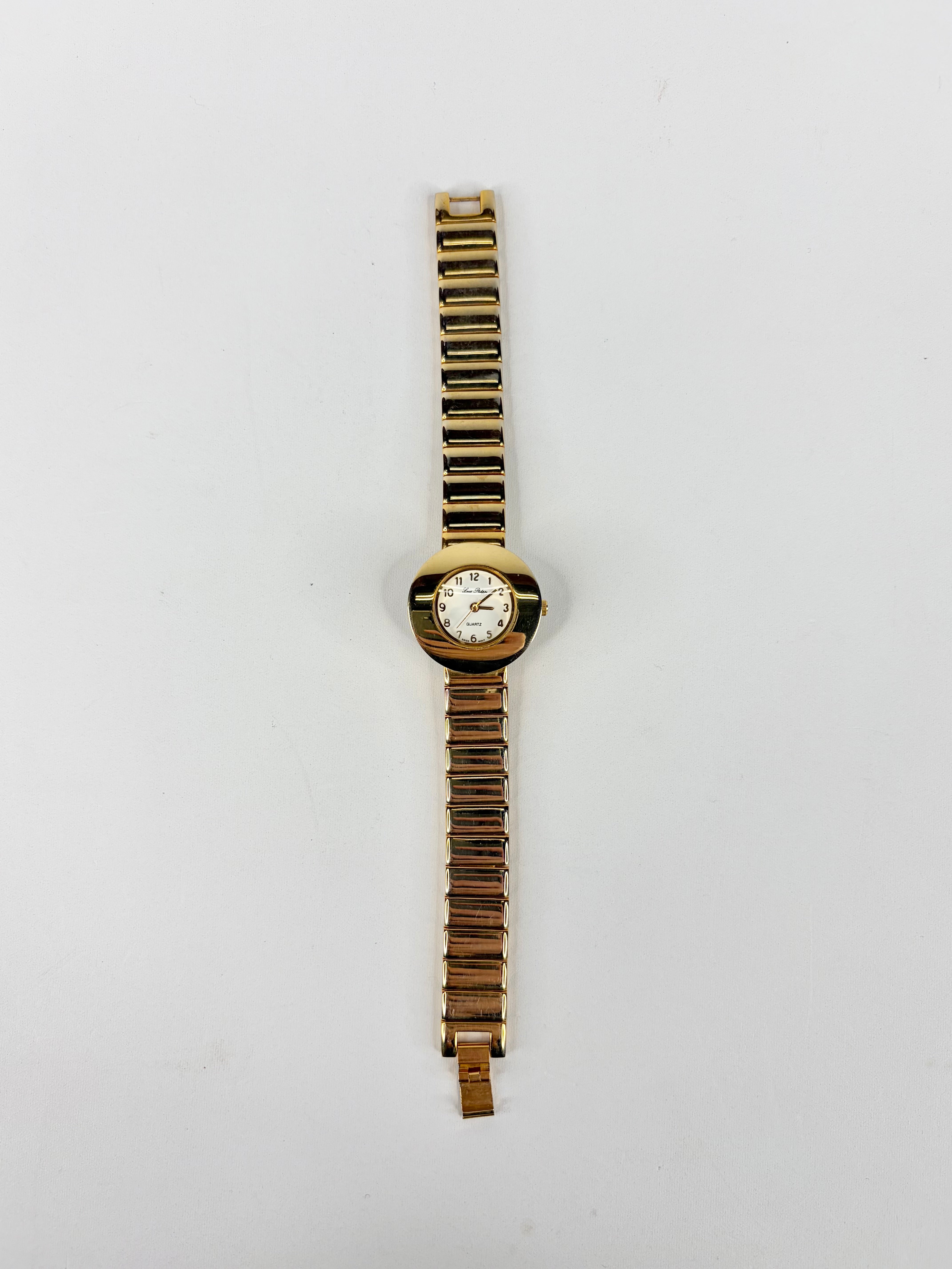 Gold watch with a white face on a light gray background