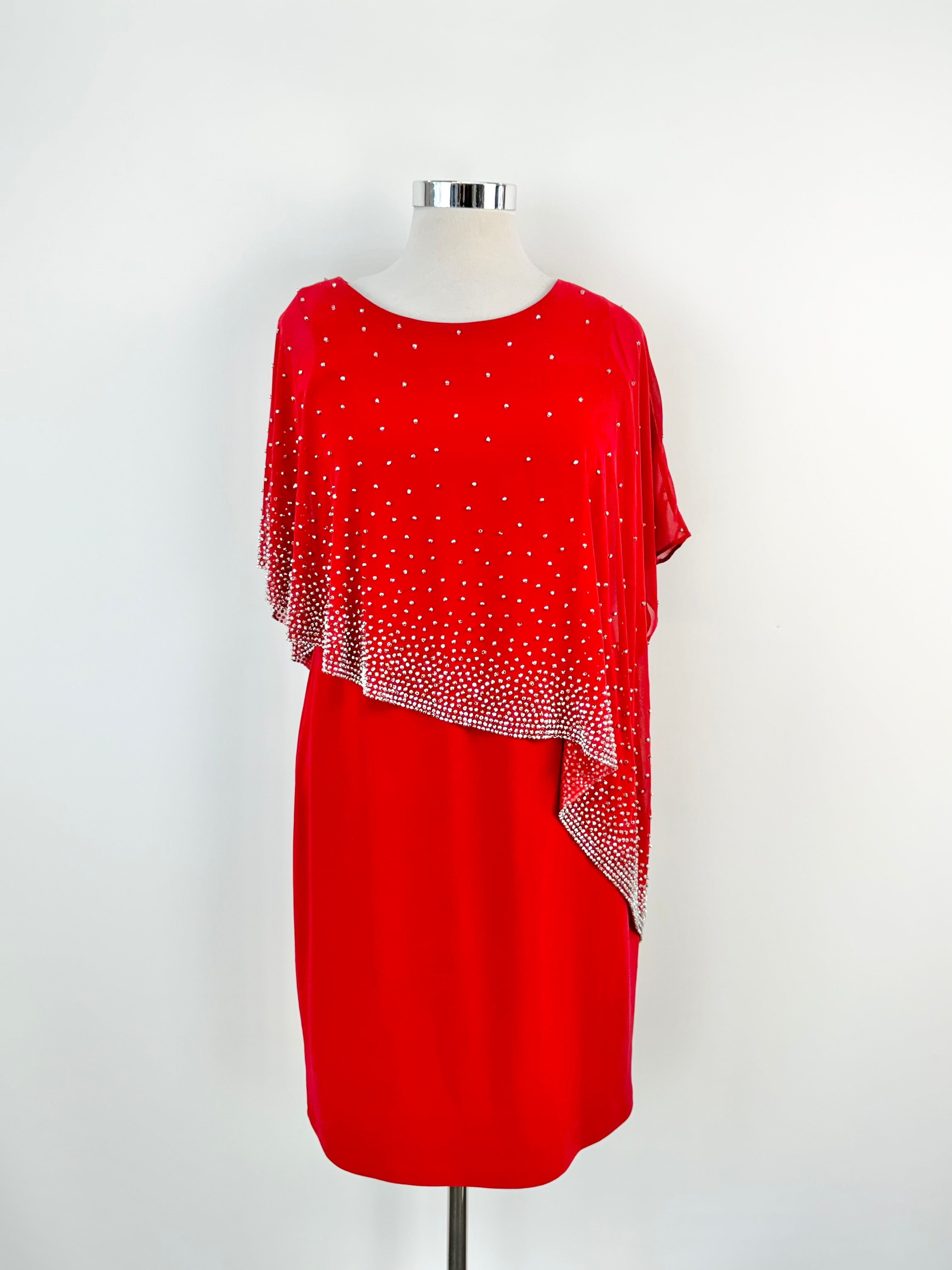 A red cocktail dress with silver sequin embellishments and a sheer built-in shawl, displayed on a mannequin.